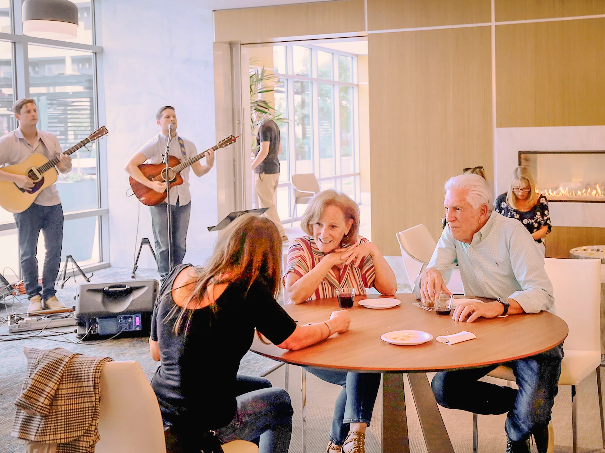 a group of people sitting at a table with a man playing guitar