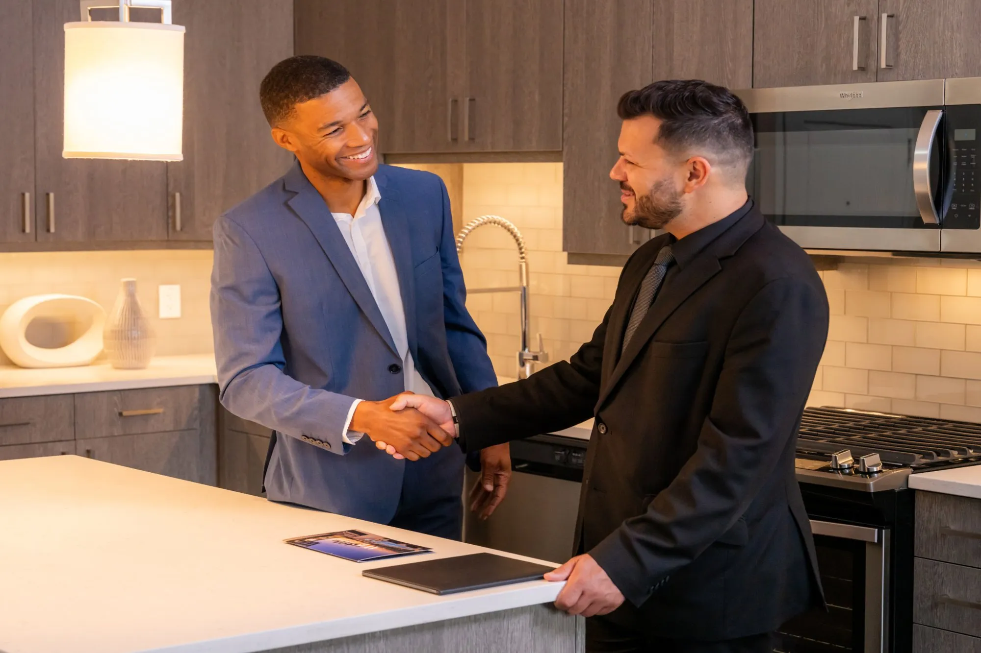 Two men shaking hands in a kitchen