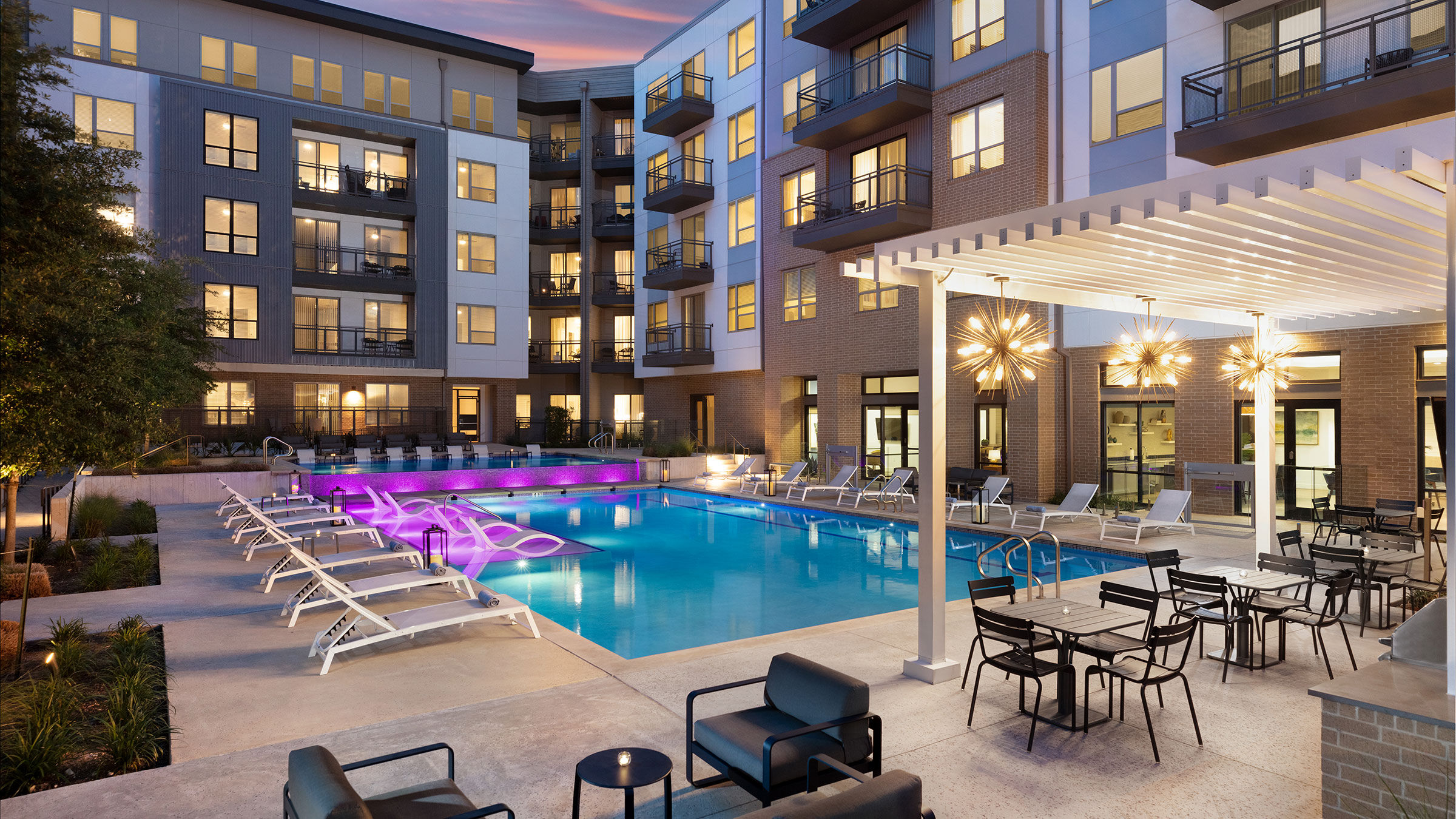 a pool with chairs and an apartment building in the background