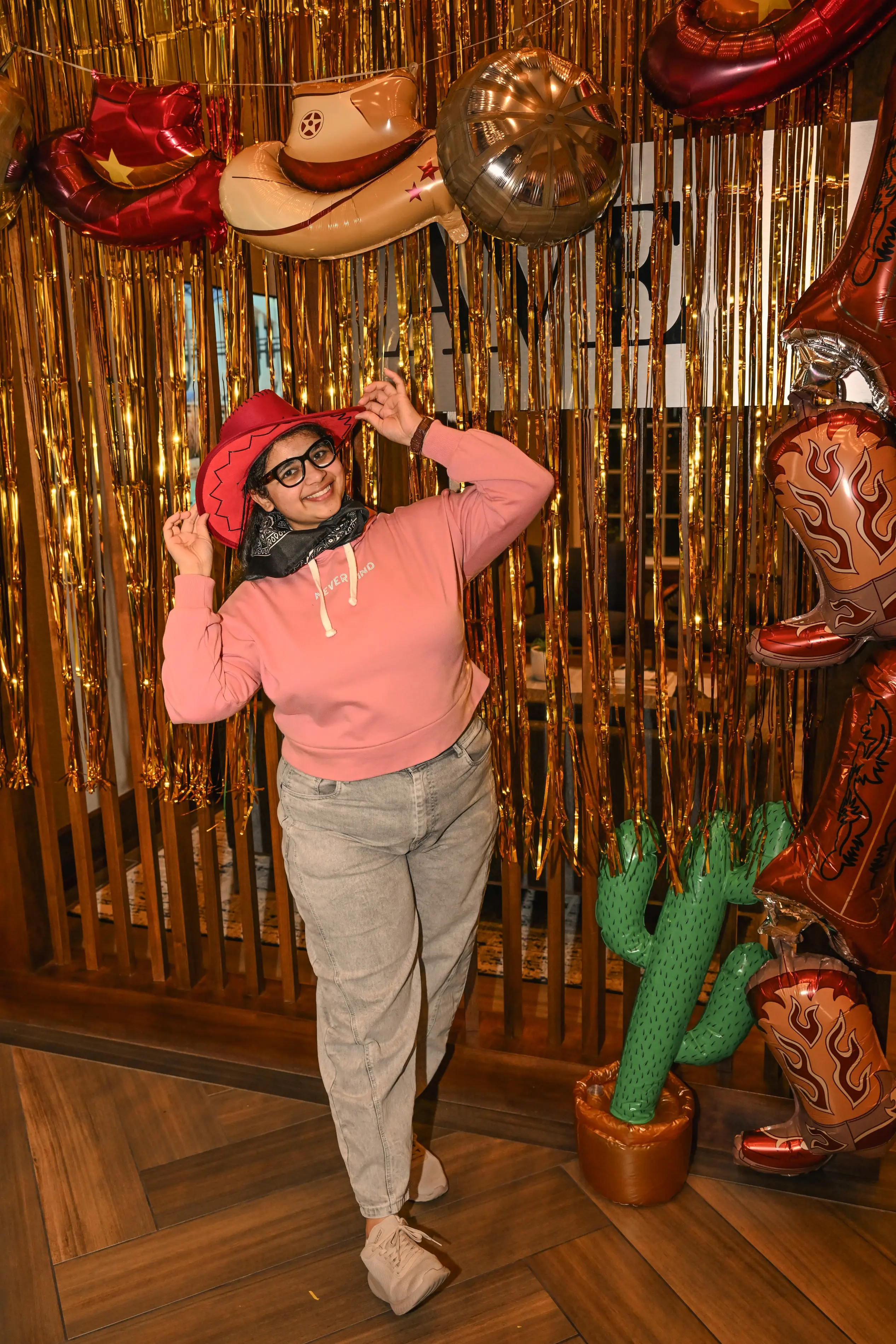 a woman wearing a cowboy hat and standing in front of a gold curtain