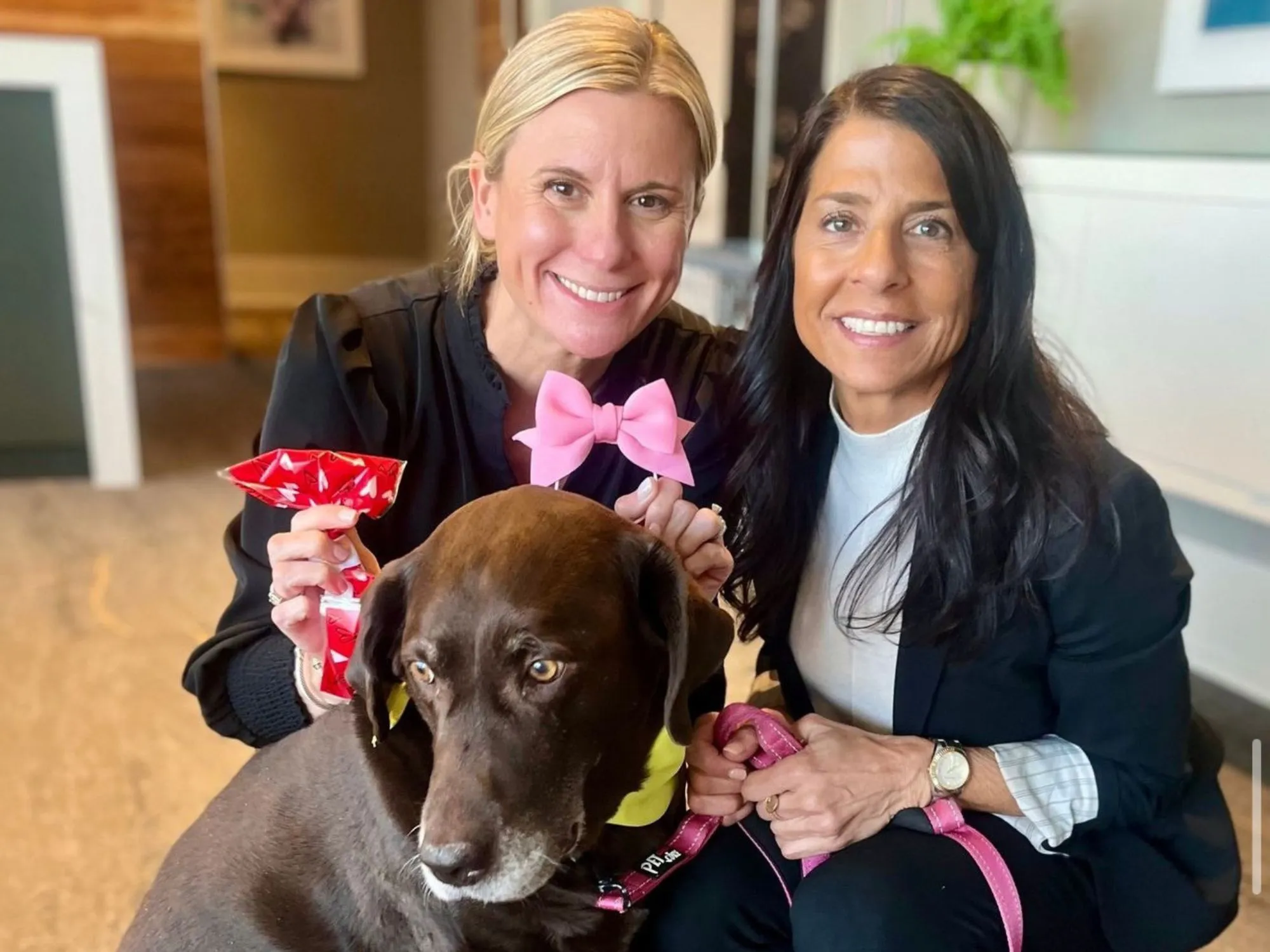 two women sitting next to a dog