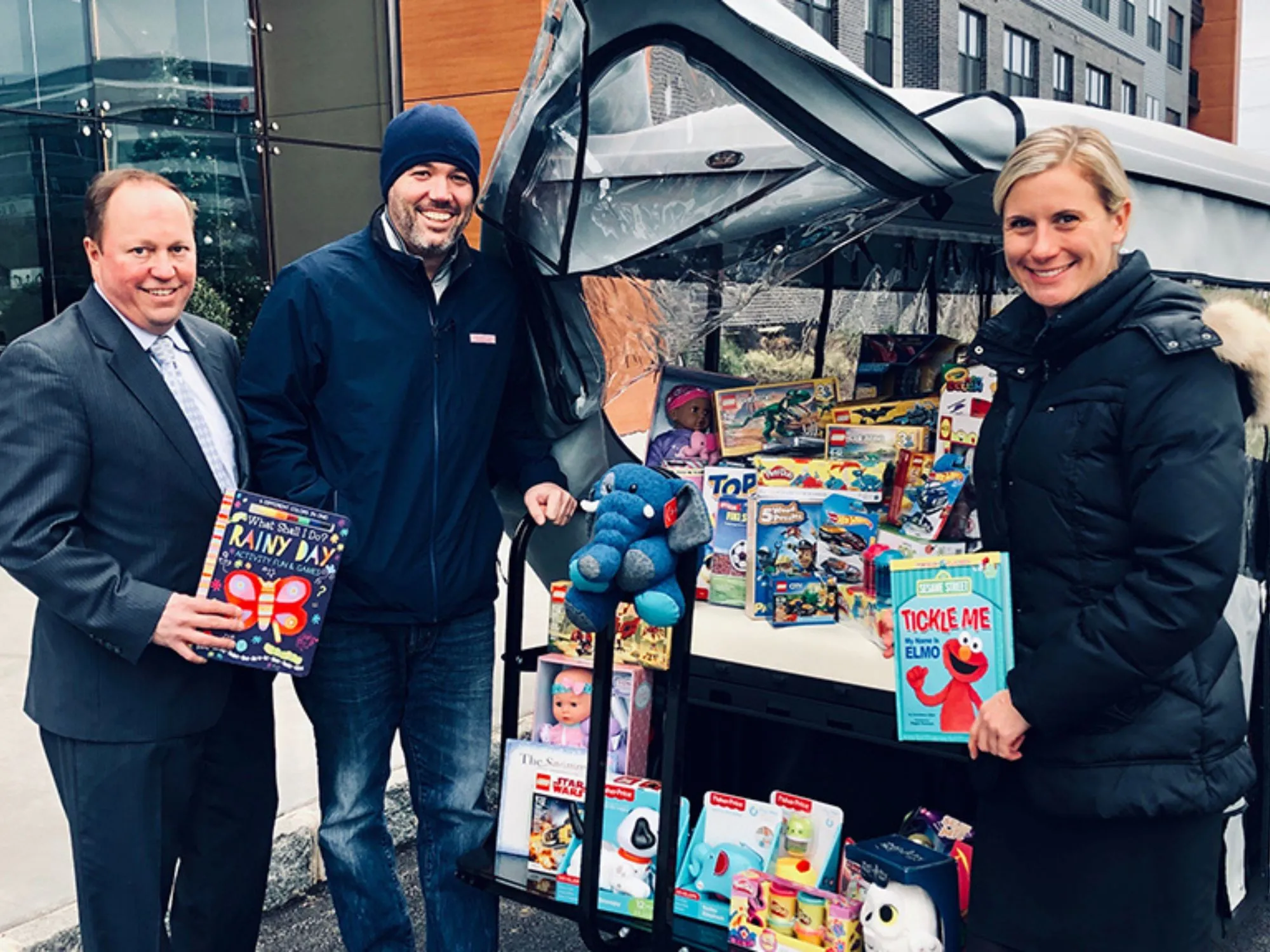 People smiling outside a car full of toy donations