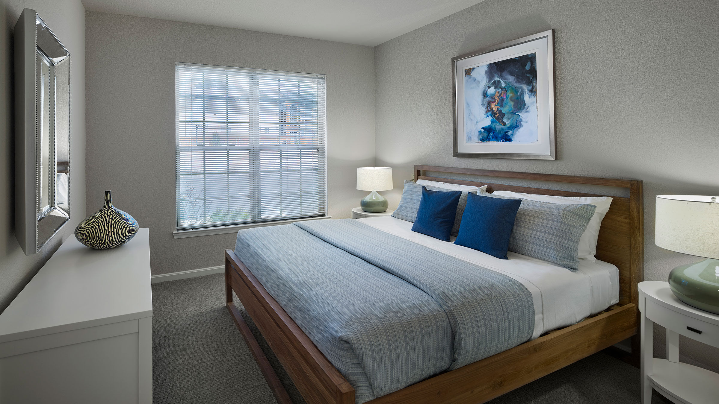 a bed with a lamp and a painting on the wall