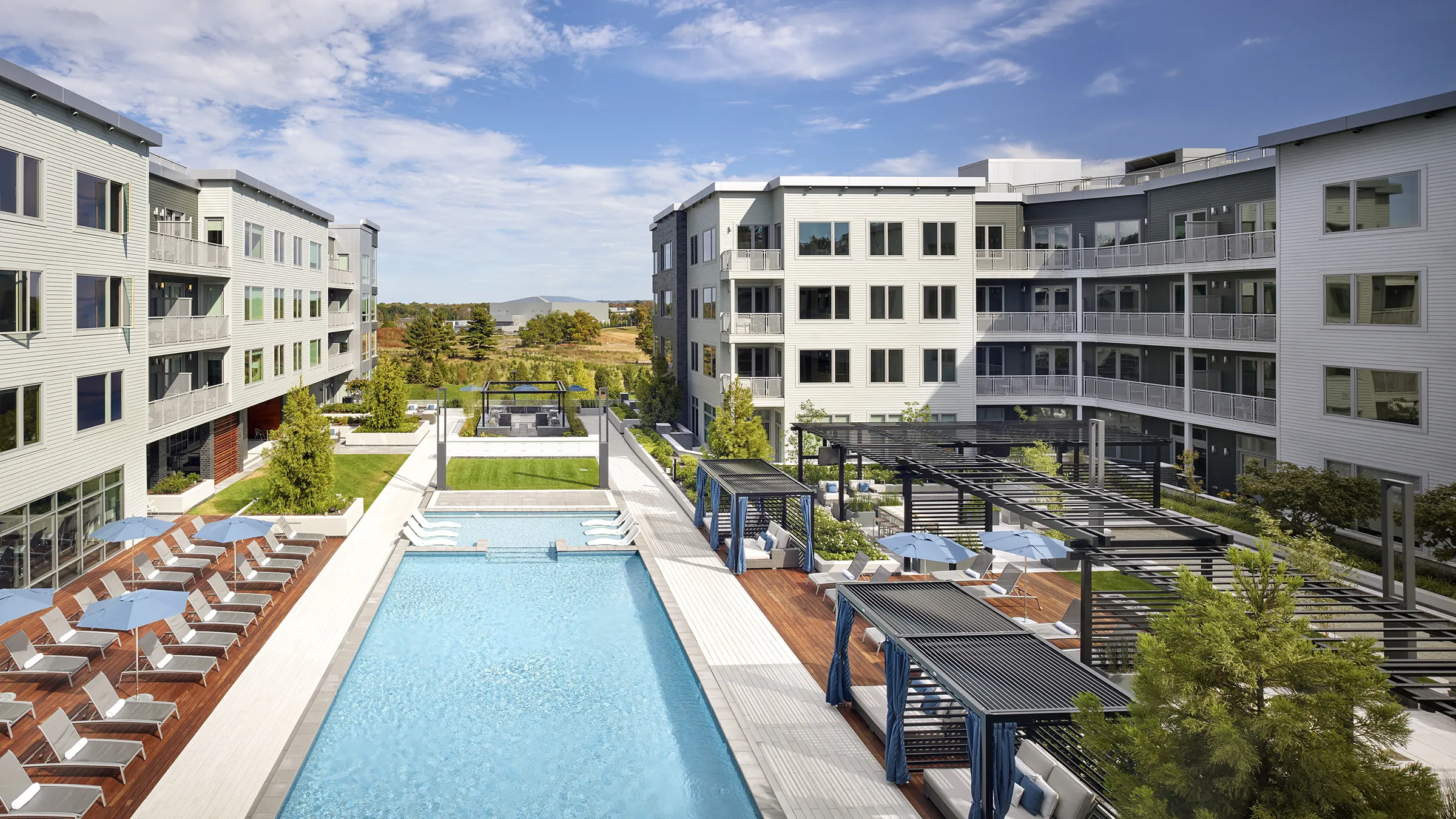 a swimming pool with a deck and chairs in front of an apartment building