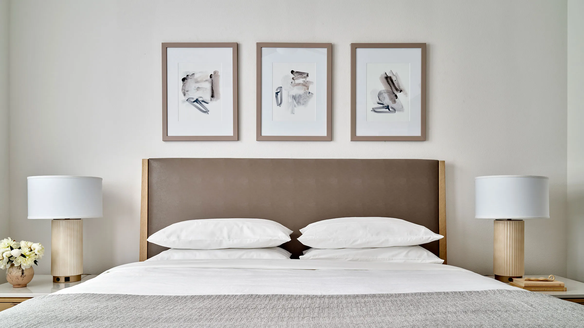 a bed with pillows and a headboard with art on the wall