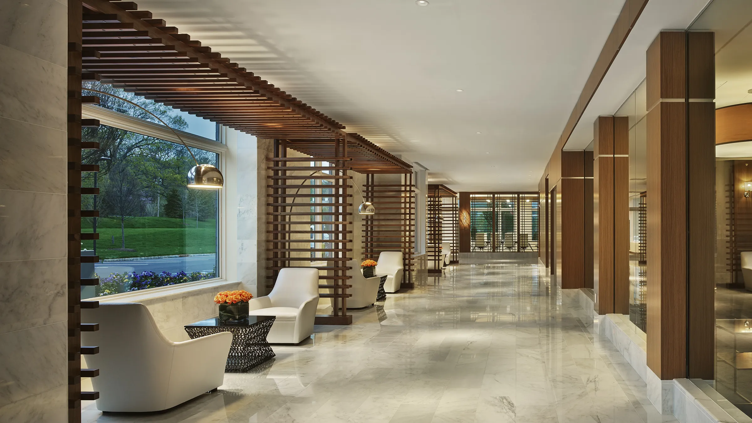a long hallway with white chairs and a large window