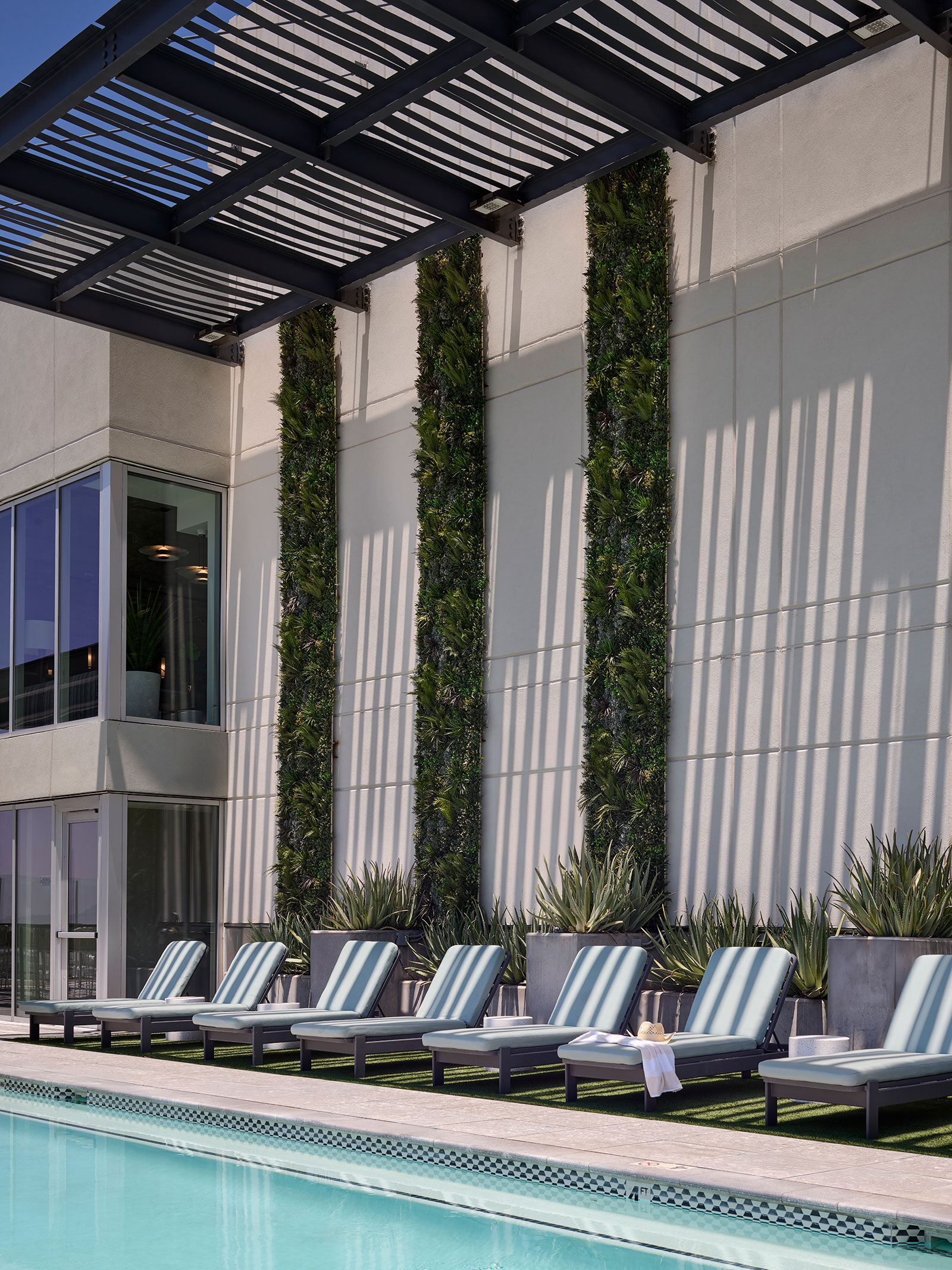 a pool with lounge chairs and plants on the side