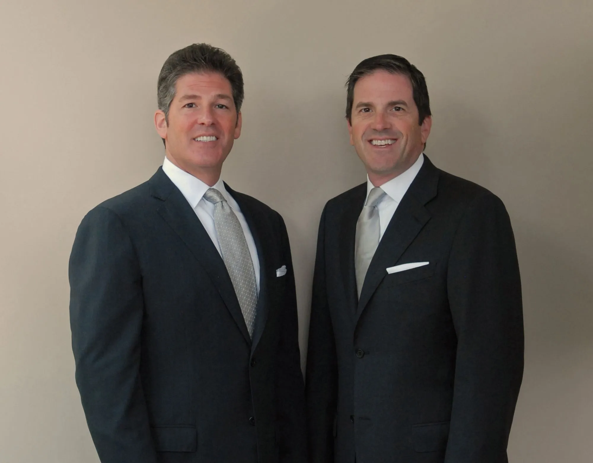 Two brothers smiling in suits.