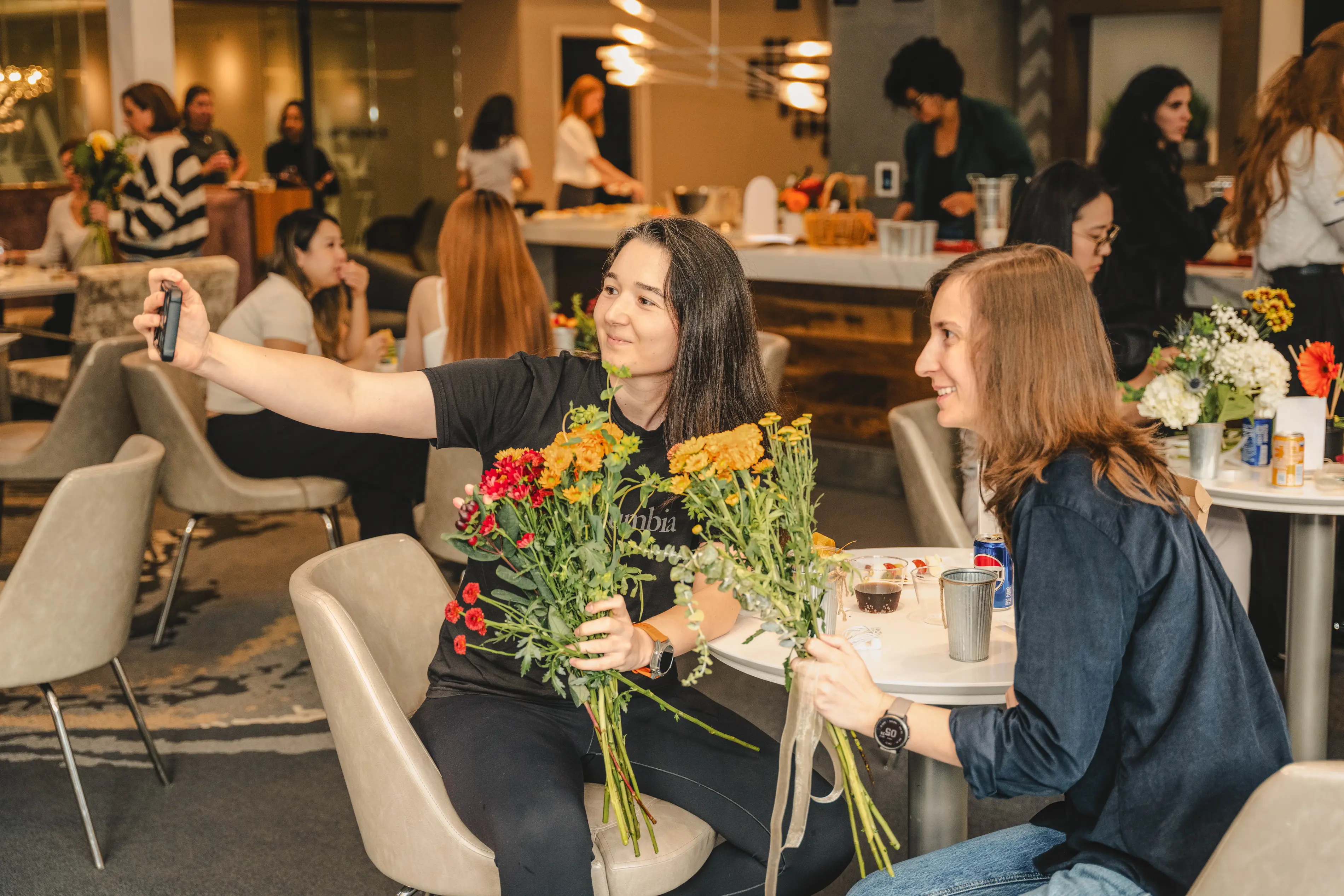 a woman holding flowers and another woman sitting at a table