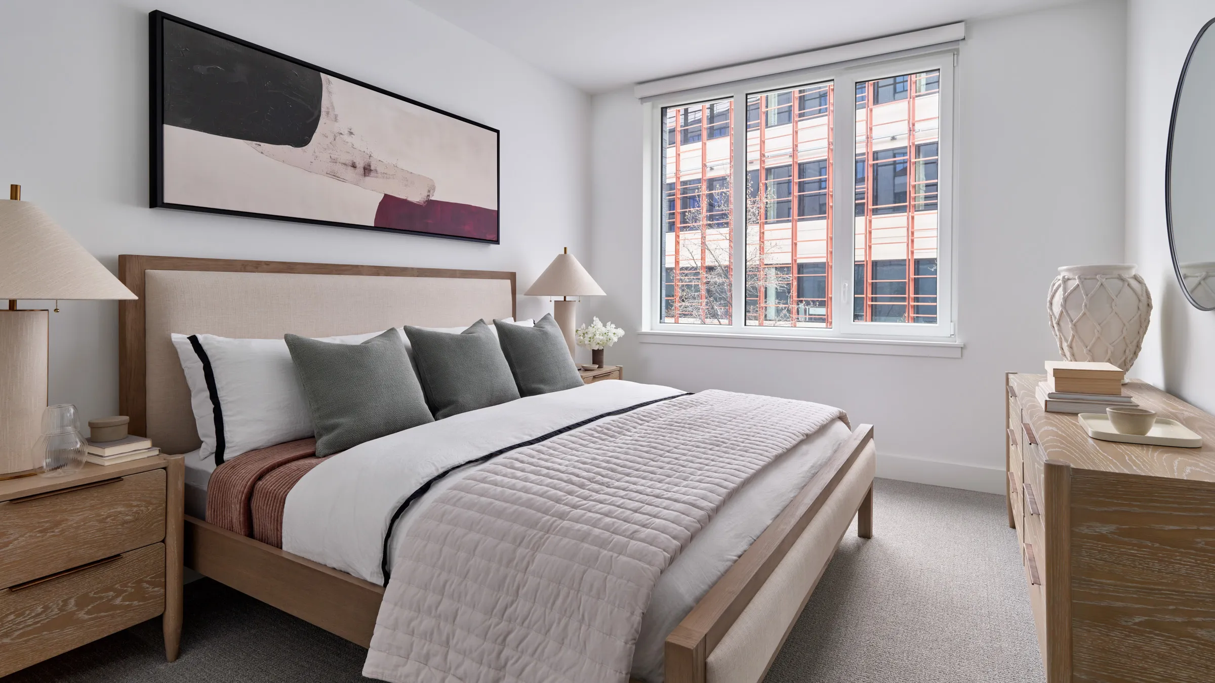 a bed with pillows and a lamp in a room with windows