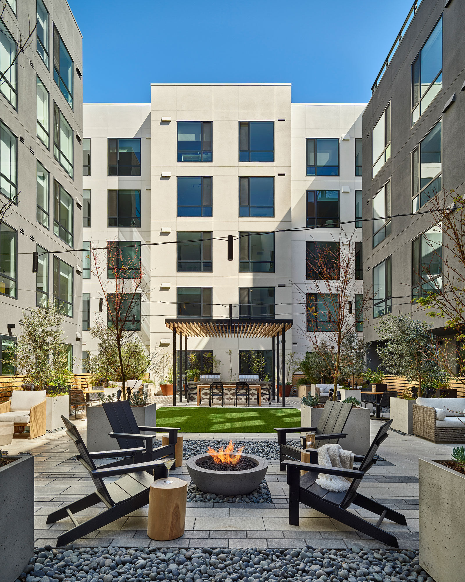 a patio with chairs and a fire pit in front of a building