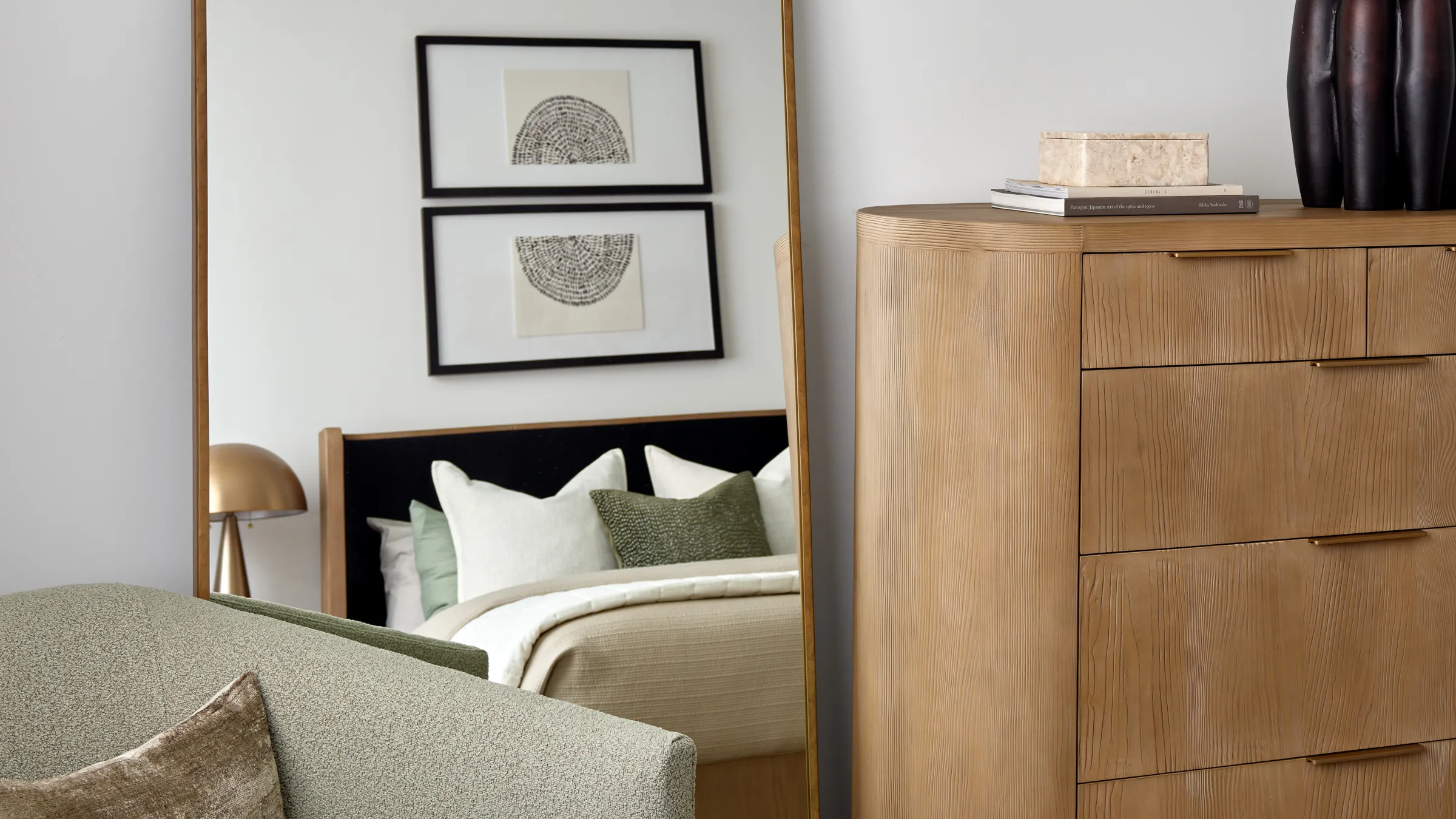 Two-bedroom apartment bedroom with a wood dresser, upholstered bed and lounge chair at AVE Normandy in Philadelphia