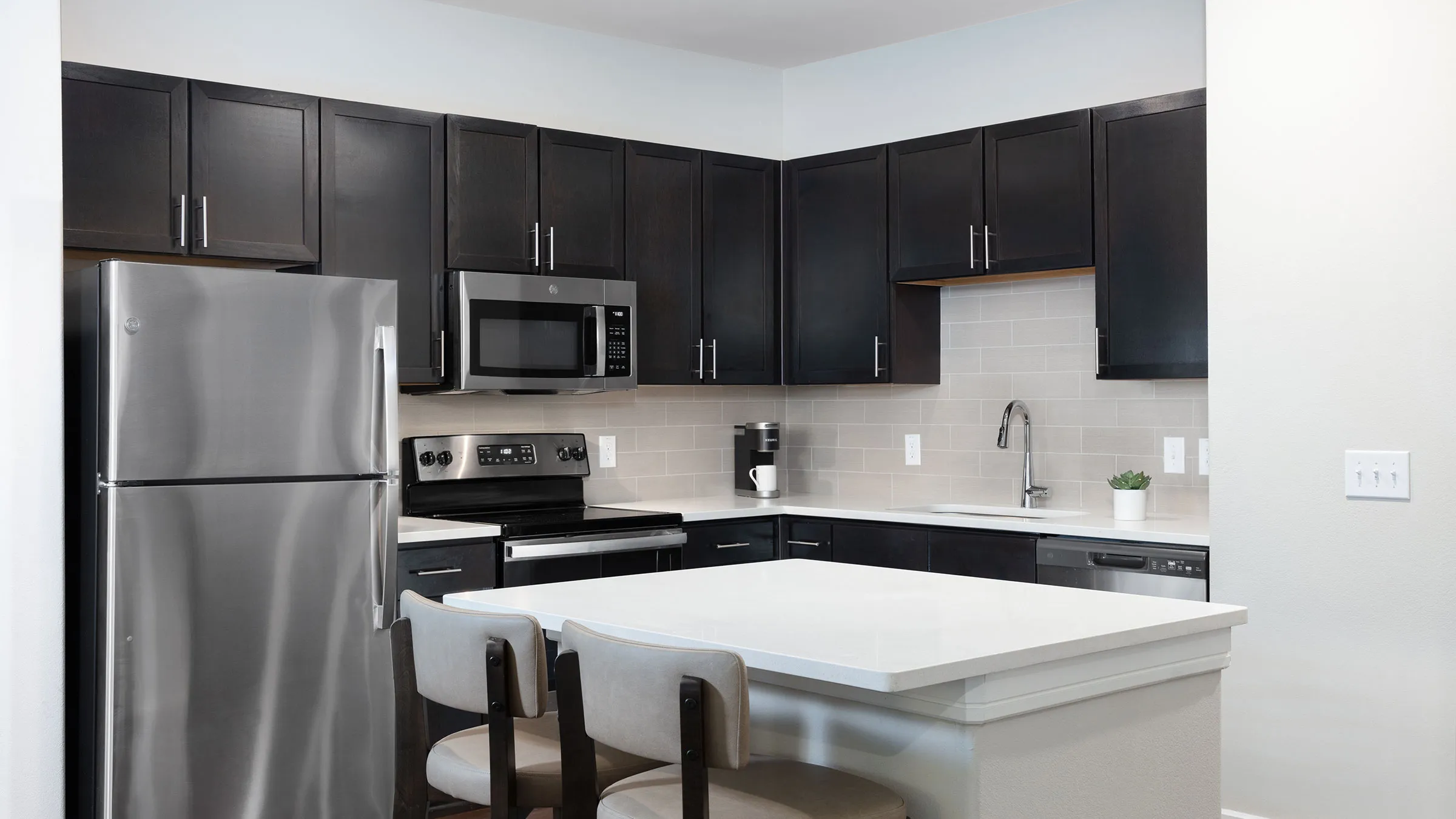a kitchen with black cabinets and a white countertop