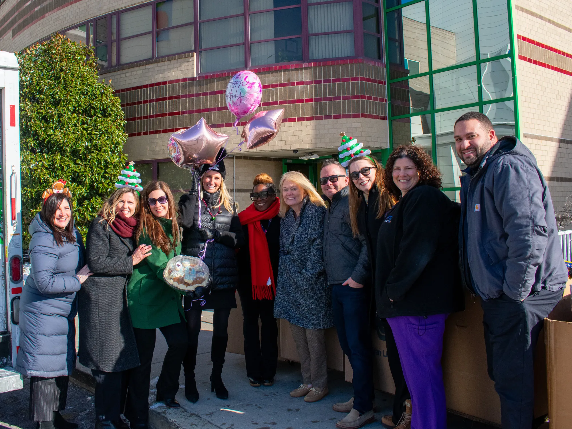 A group of team members holding balloons and cake at St. Christopher's Hospital for Children