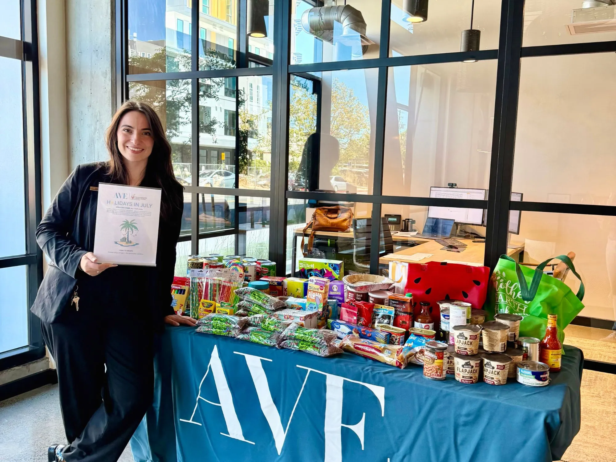 A woman smiling in front of a table of food donations