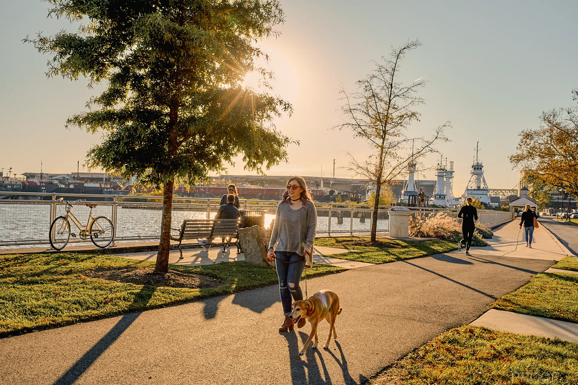 a woman walking a dog on a path at the Navy Yard in Philadelphia, PA