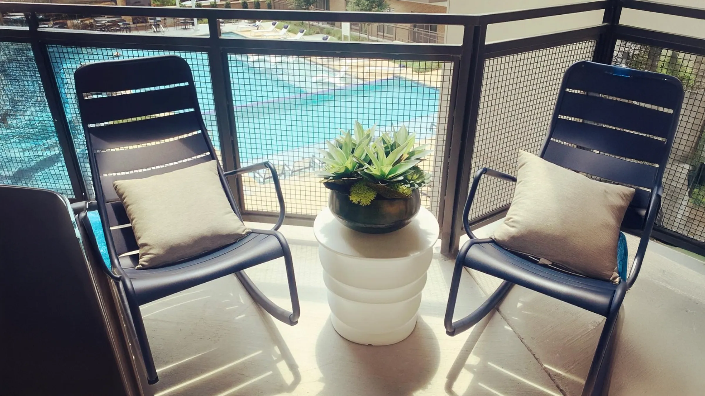 chairs on a balcony with a pool in the background