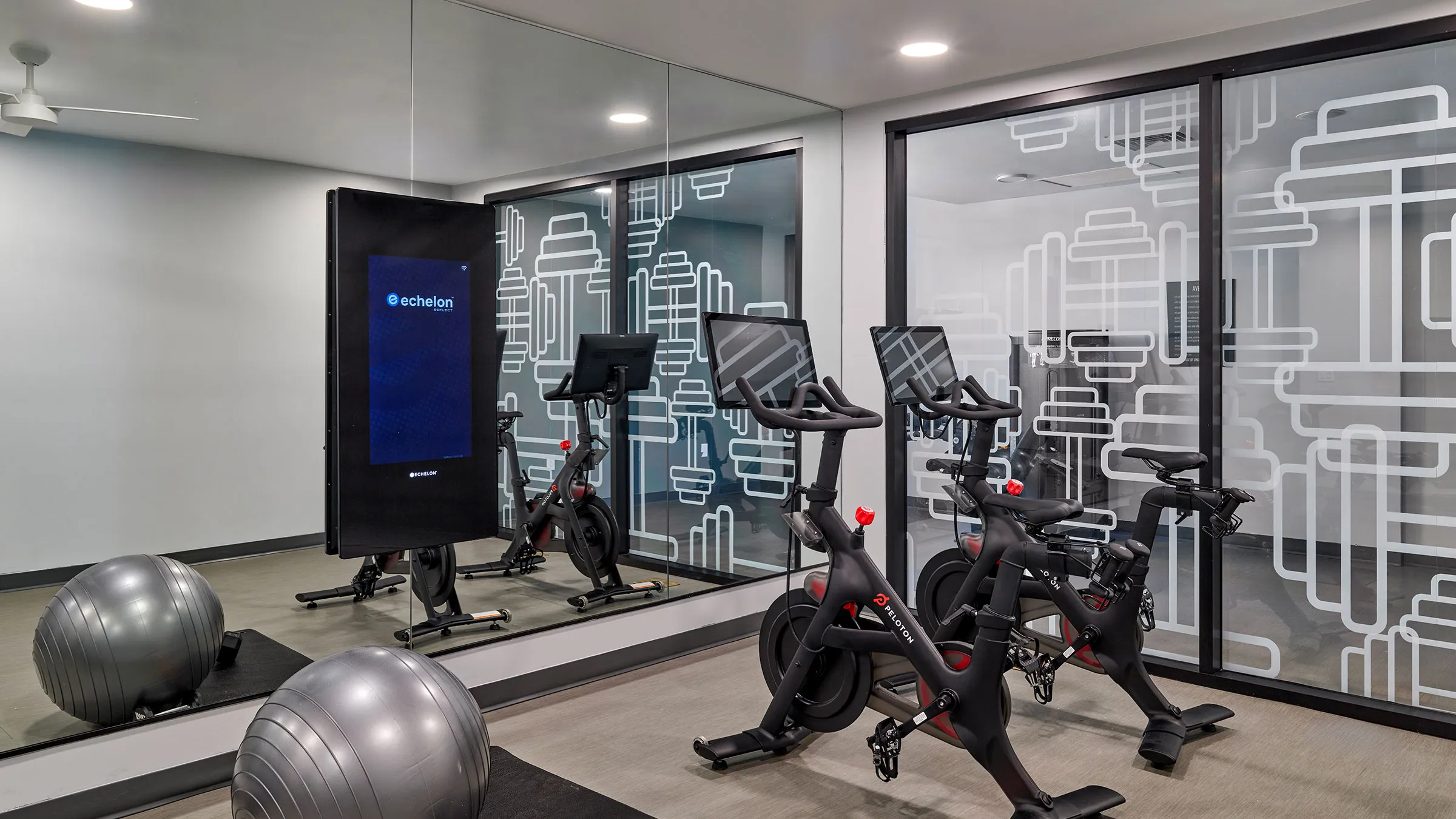a room with exercise bikes and a large screen