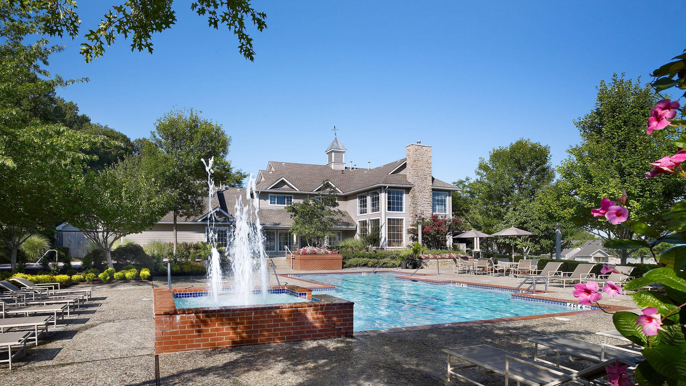 a pool with a fountain in front of a house