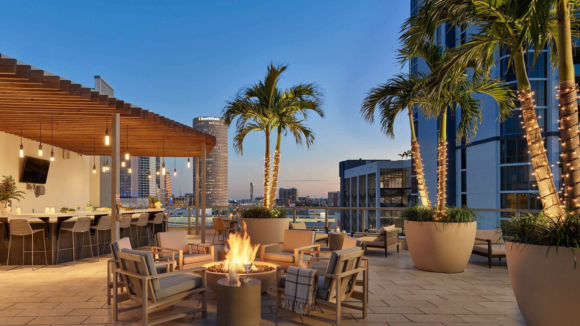 a patio with chairs and a fire pit on a rooftop