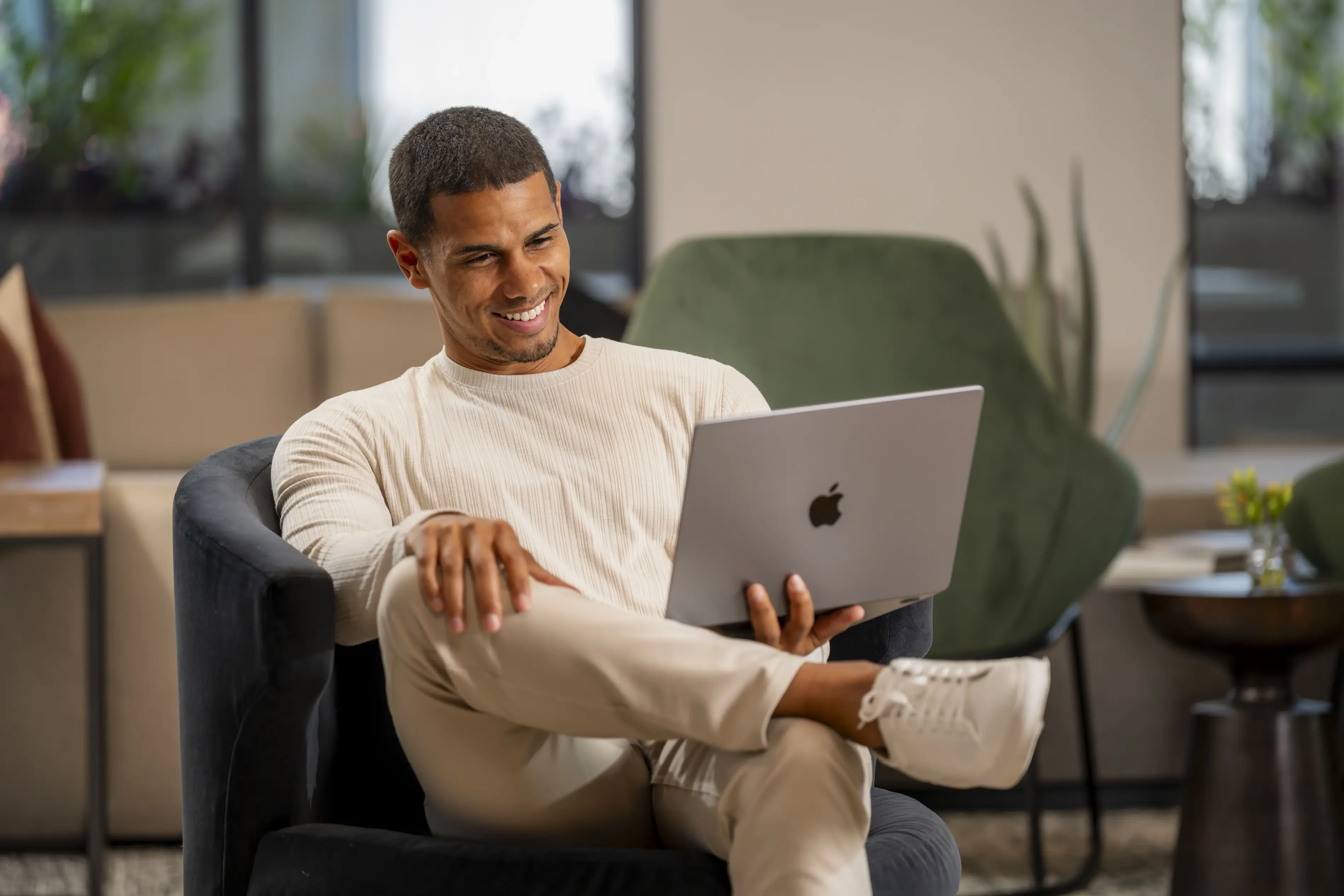 a man sitting in a chair with his legs crossed and a laptop