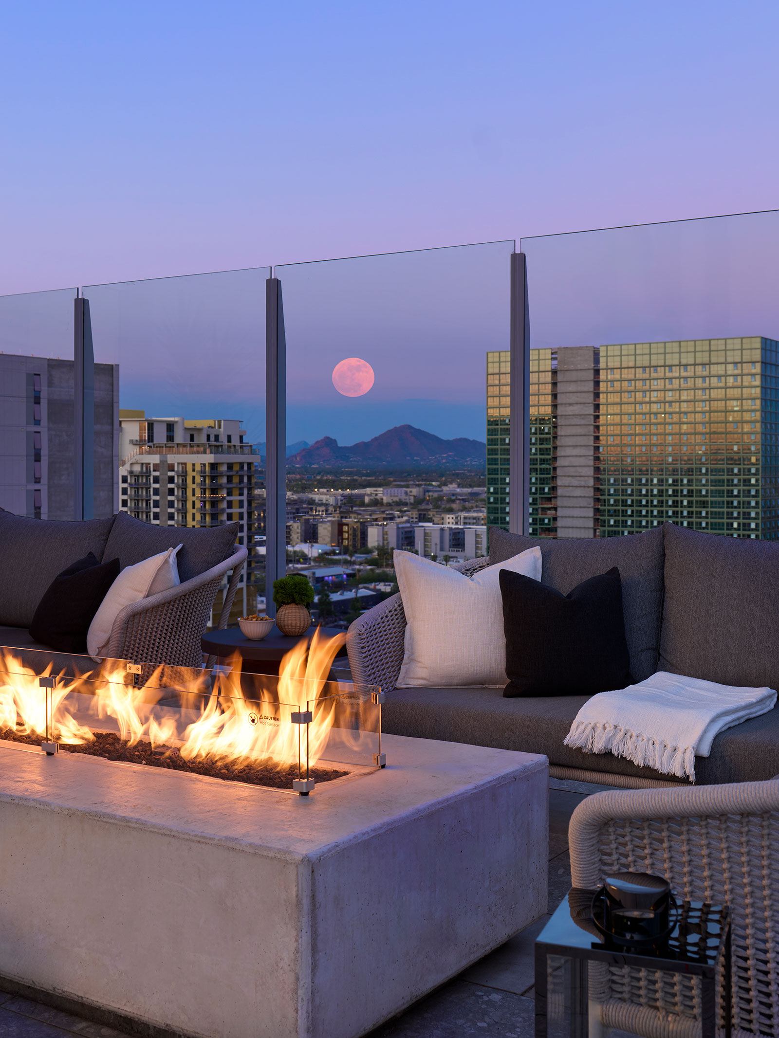 a fire pit on a rooftop with a view of a city and the moon