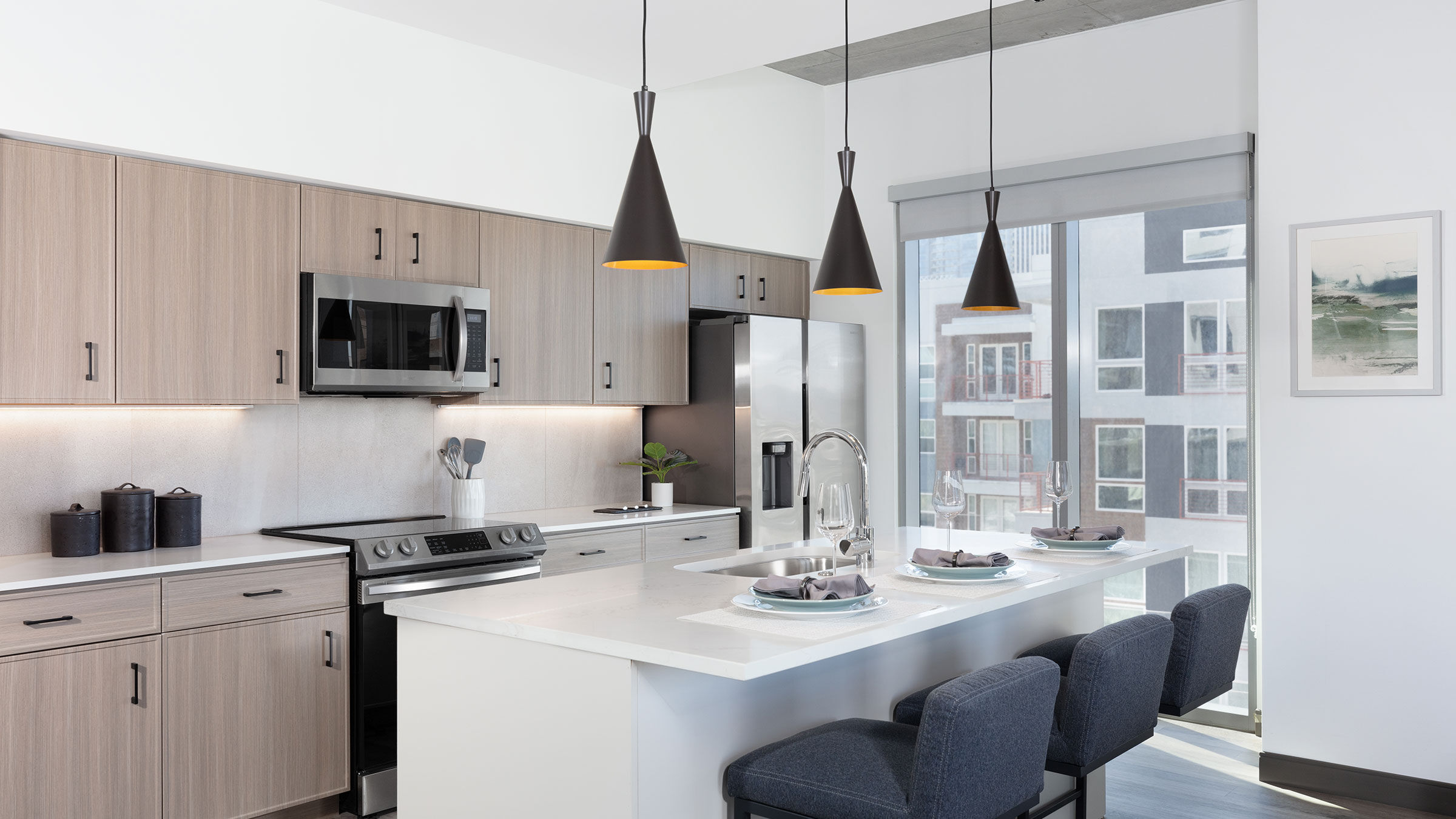 a kitchen with a white island and black pendant lights