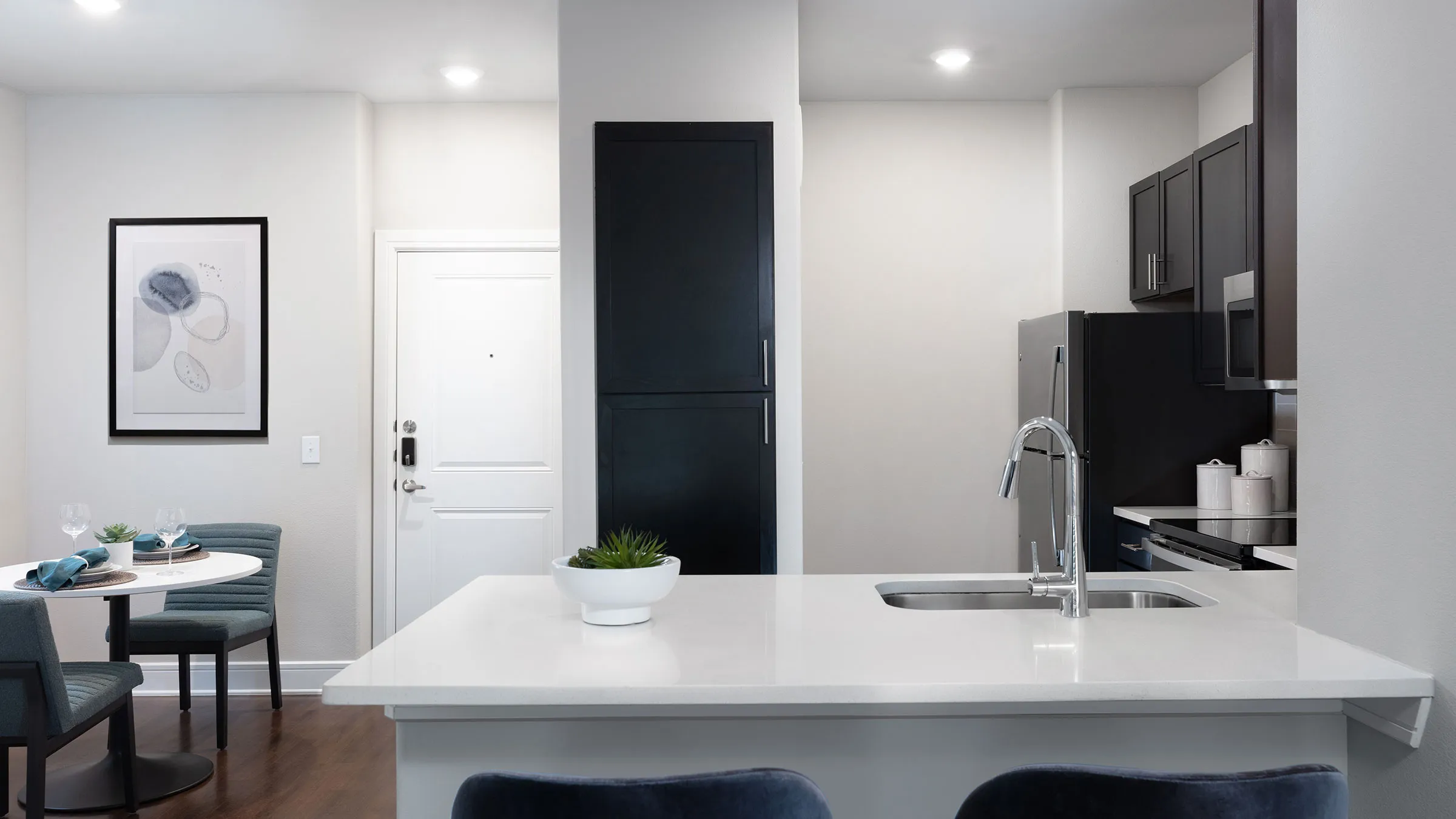a kitchen with a white countertop and black chairs