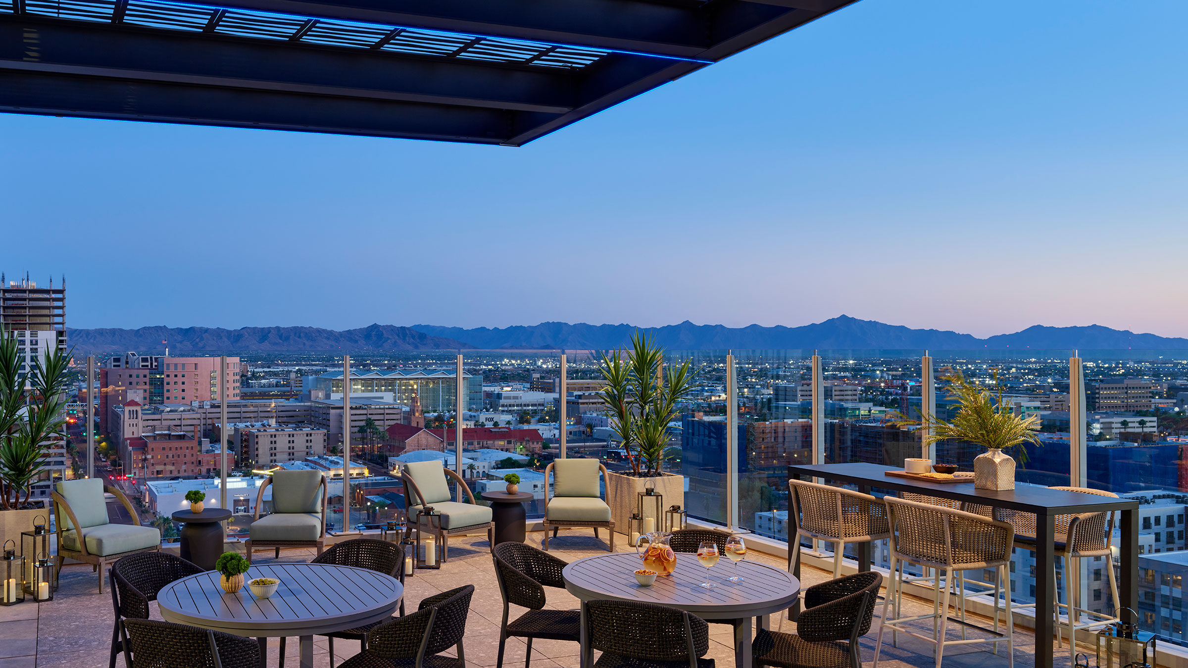 a rooftop patio with chairs and tables and a city view