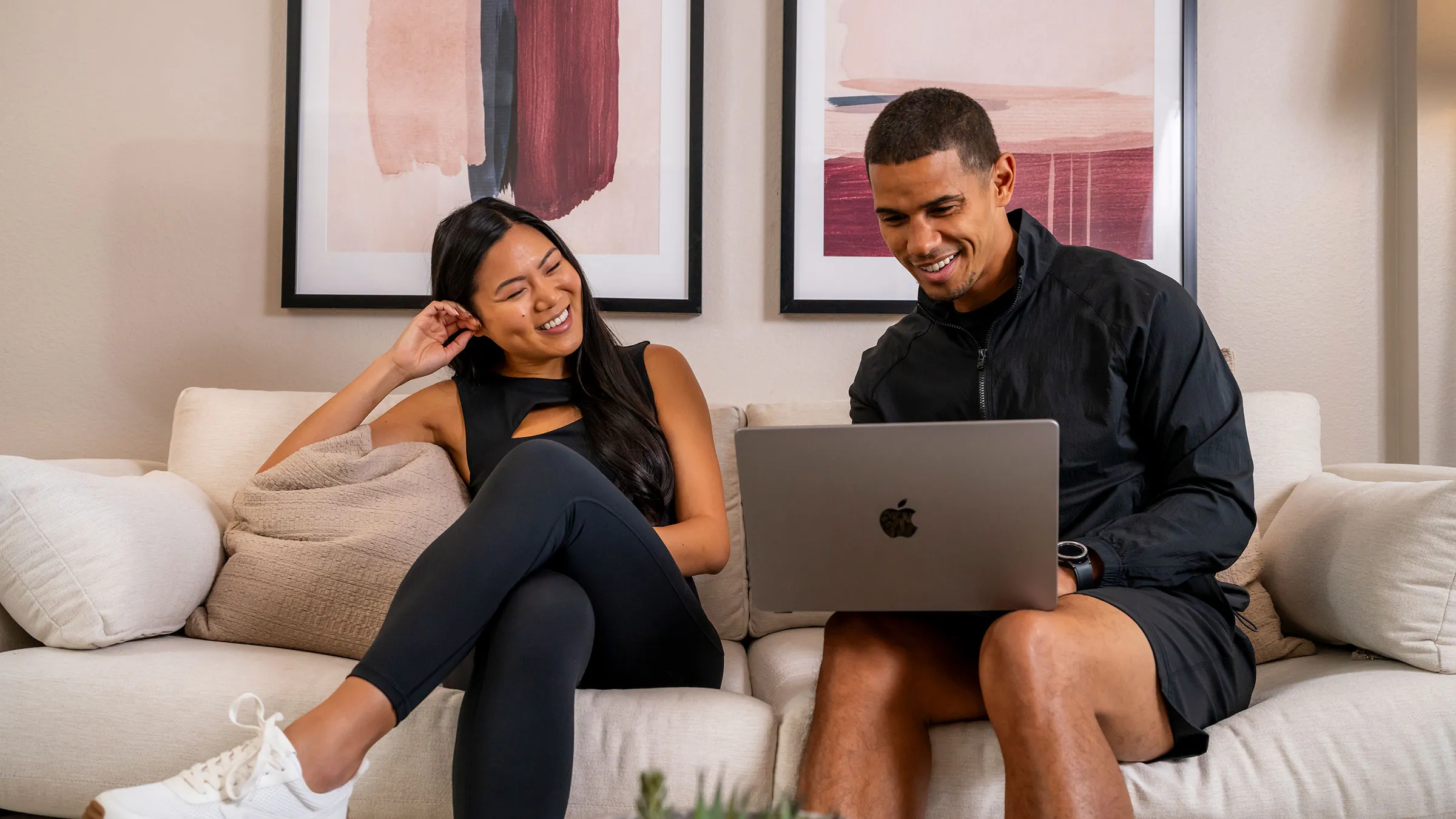 a man and woman sitting on a couch with a laptop
