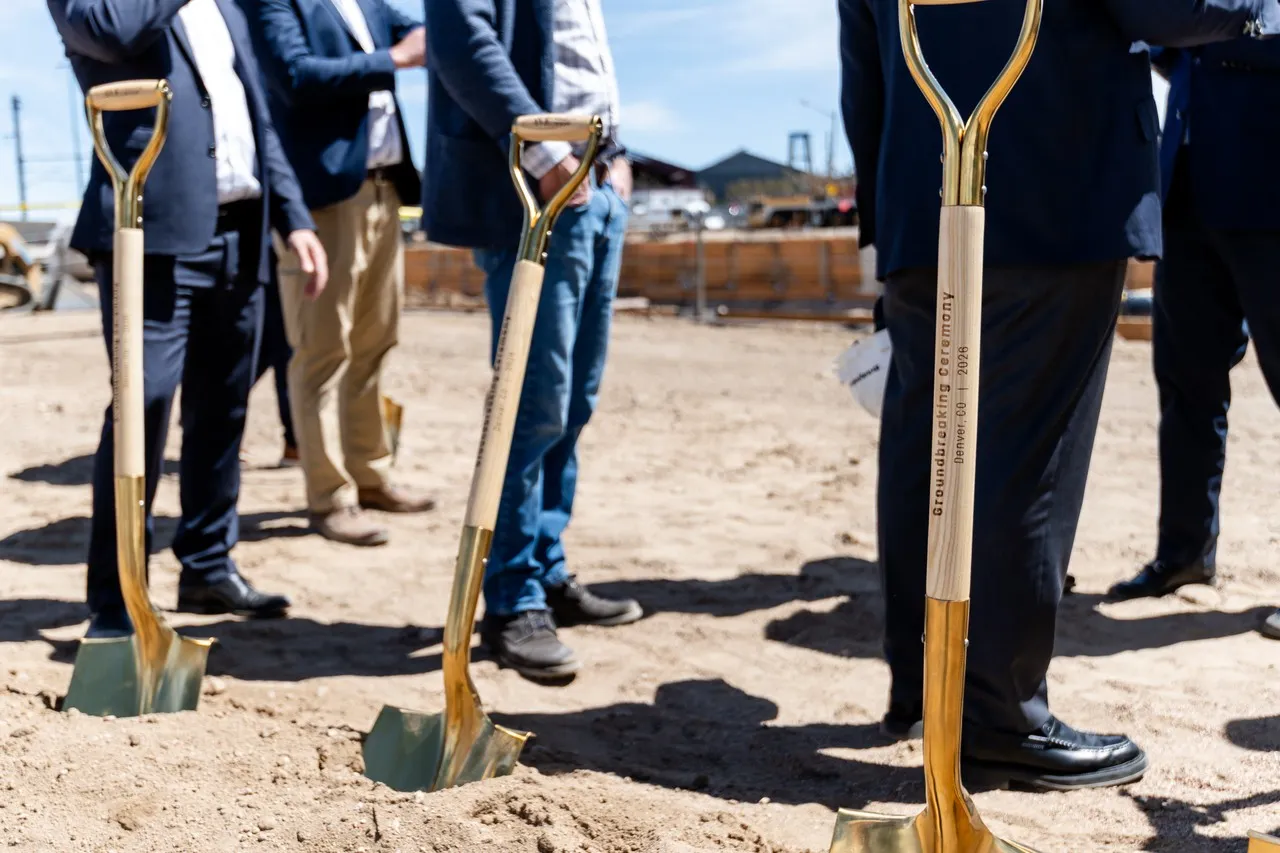 a group of people standing in a dirt area with shovels