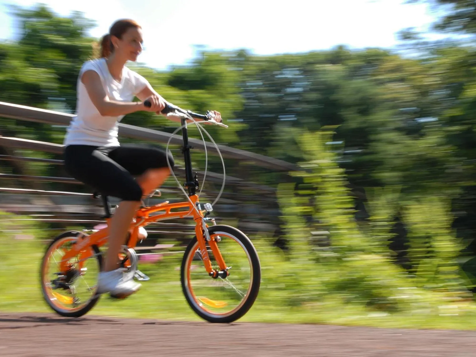 woman riding an orange bike outside