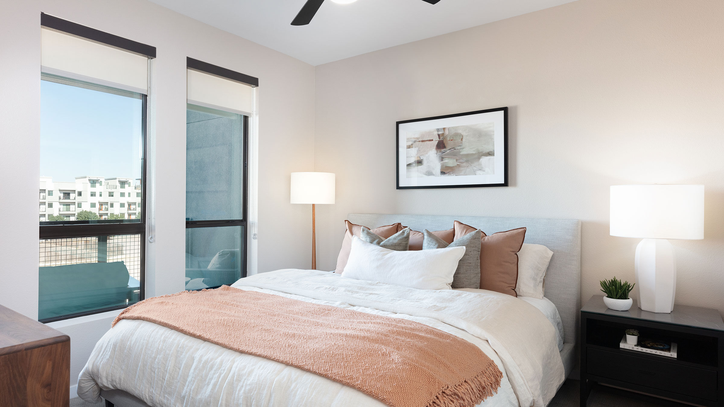 a bed with a fan and a painting on the wall