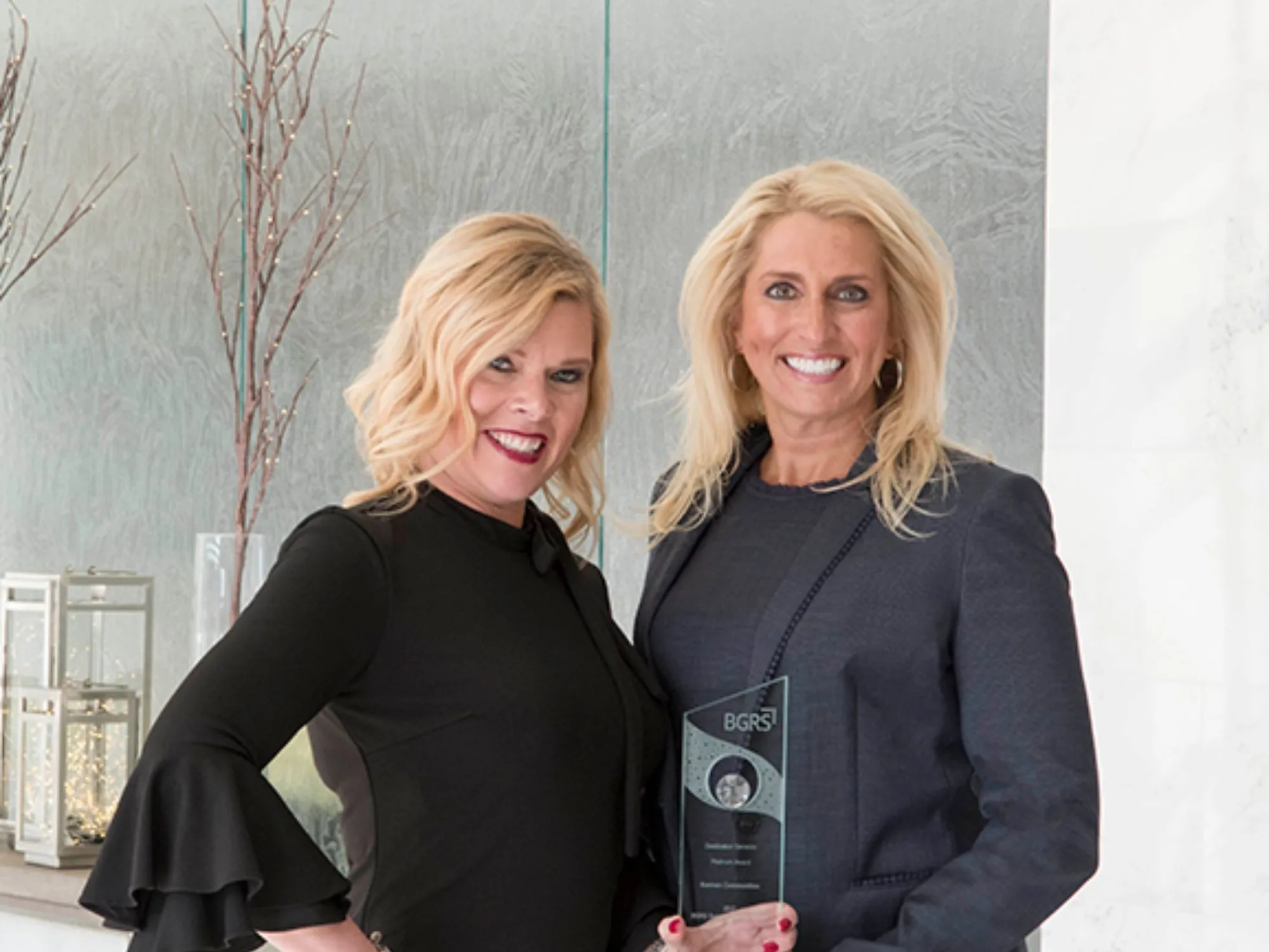 Two women smiling with an award