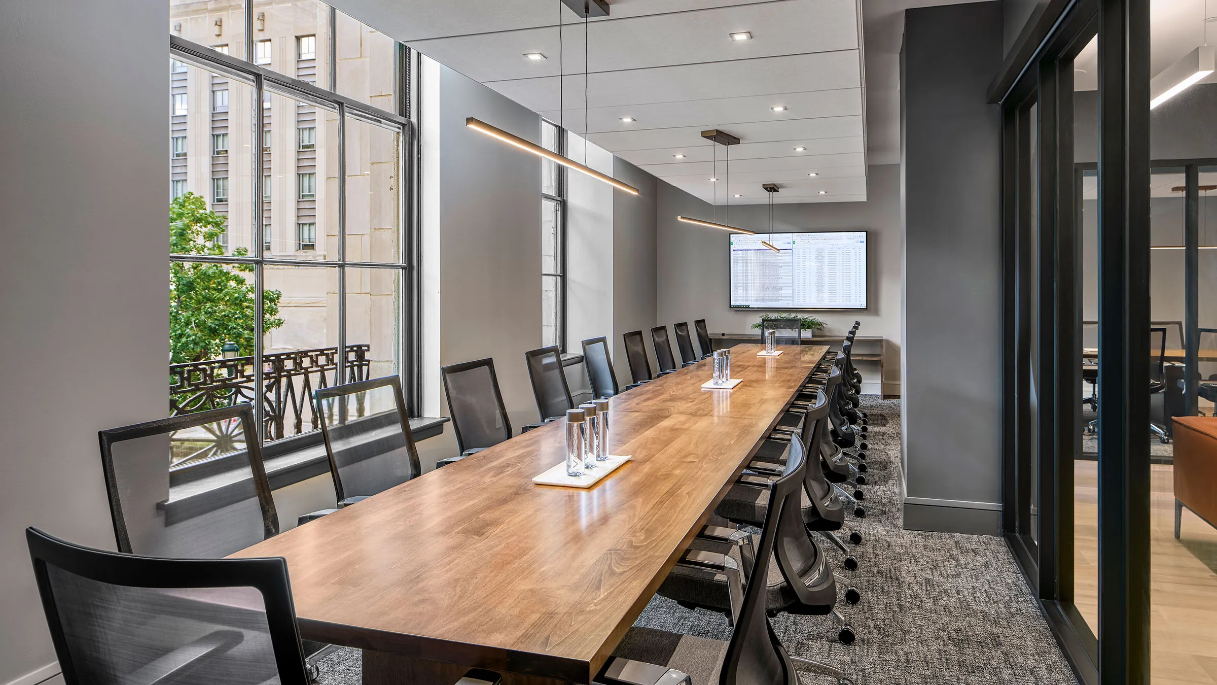 a long conference table with chairs and a screen