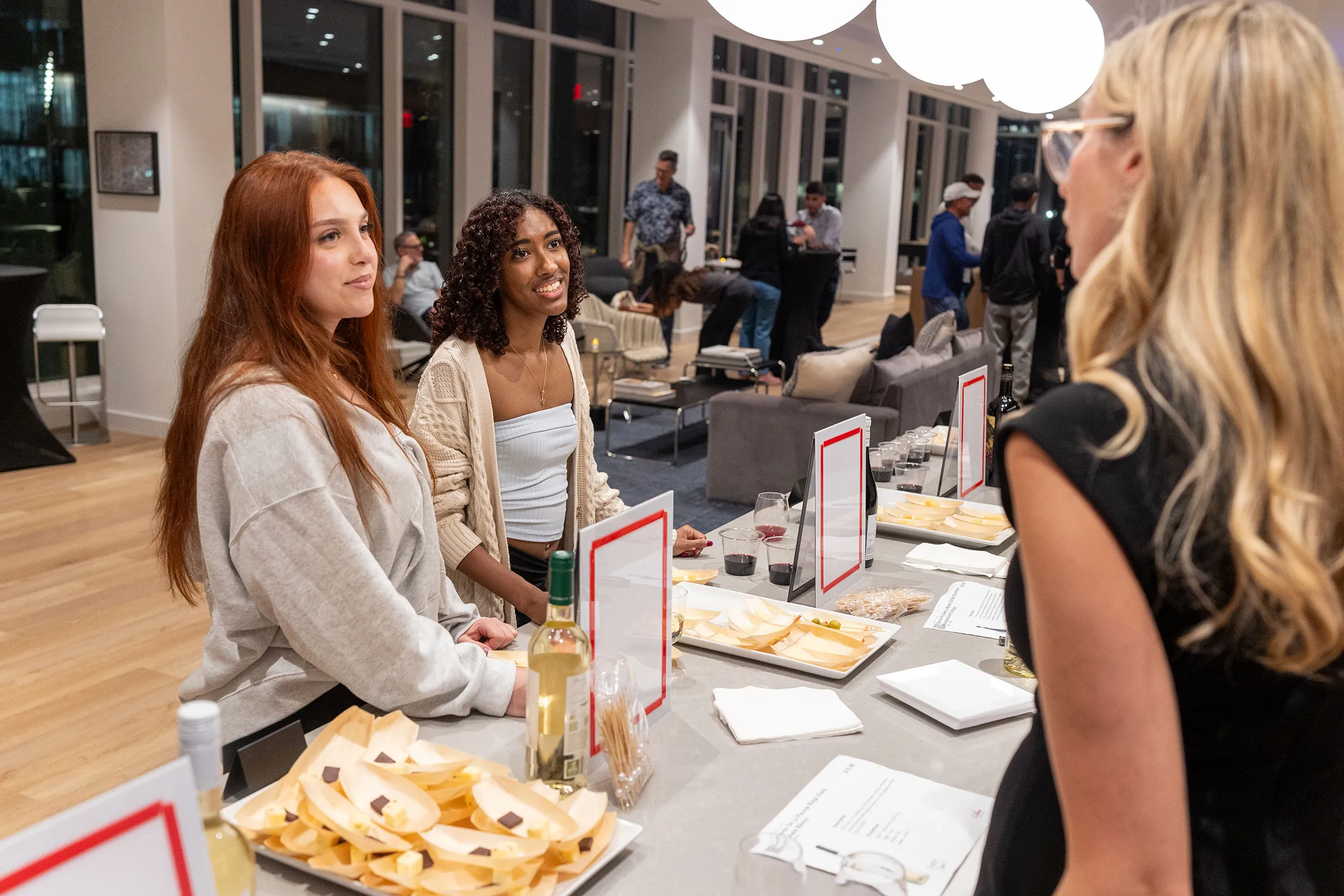 a group of women sitting at a table with food and drinks