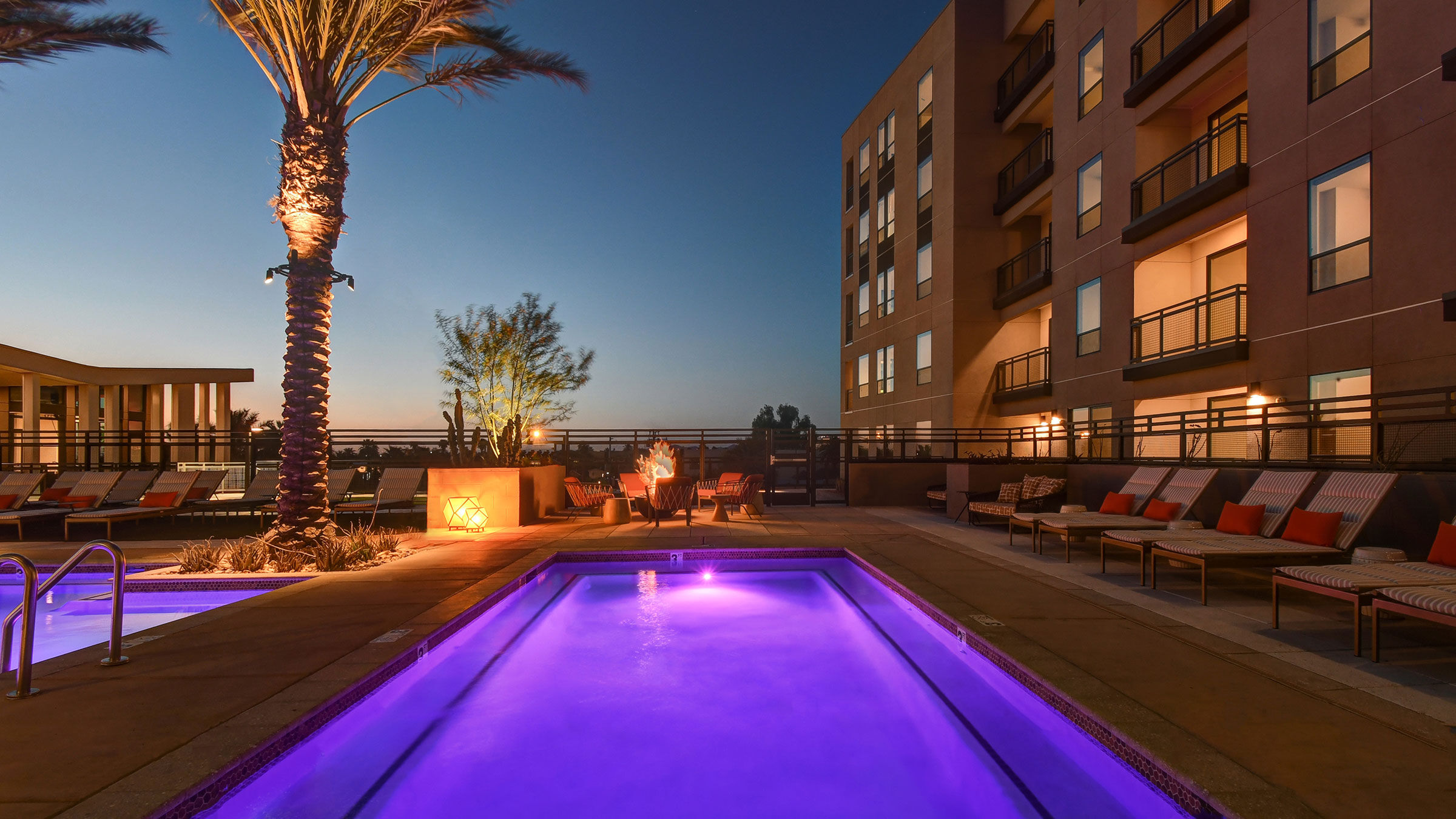 a pool with purple lights in front of a building