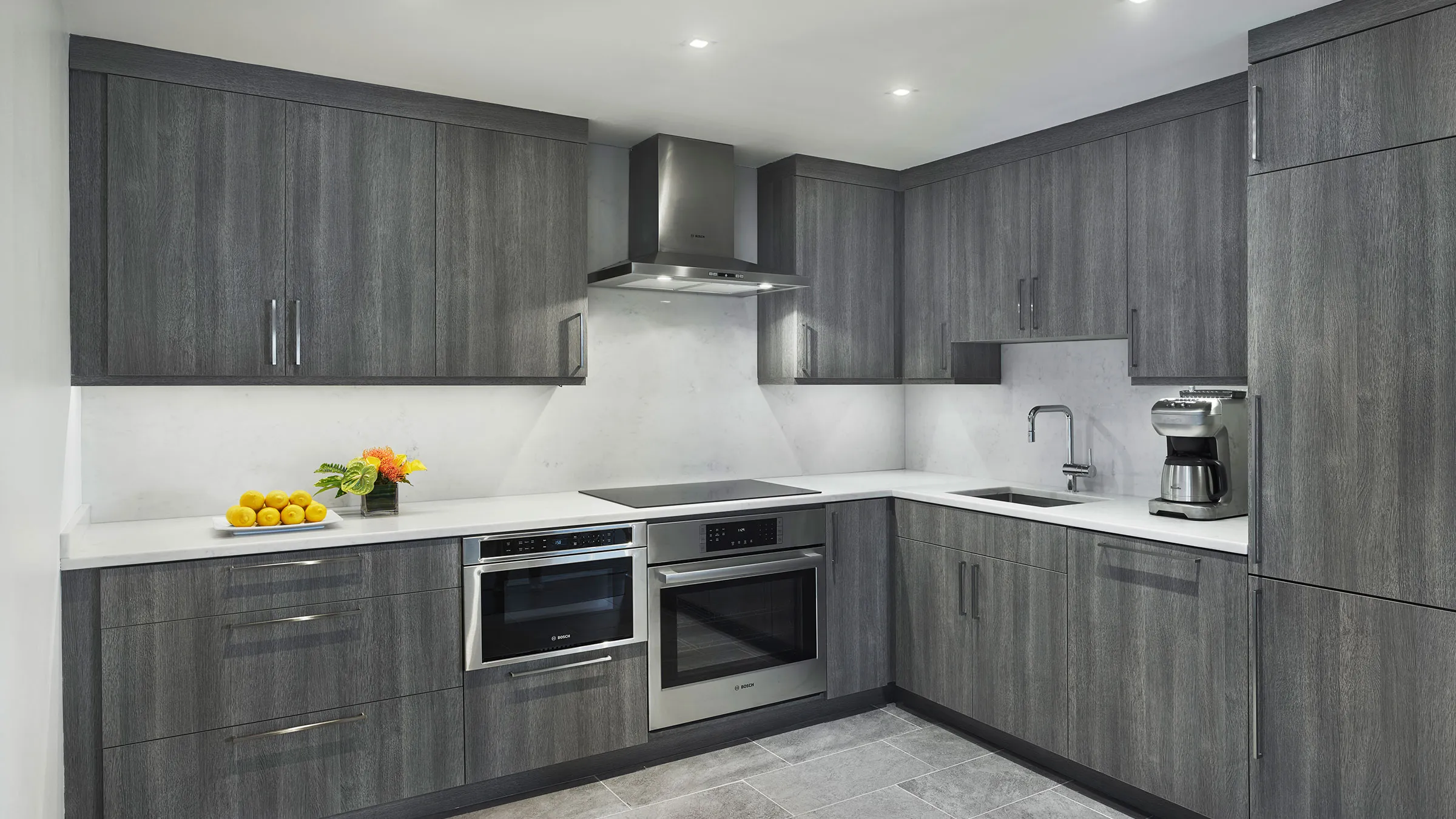 a kitchen with grey cabinets and white counter tops