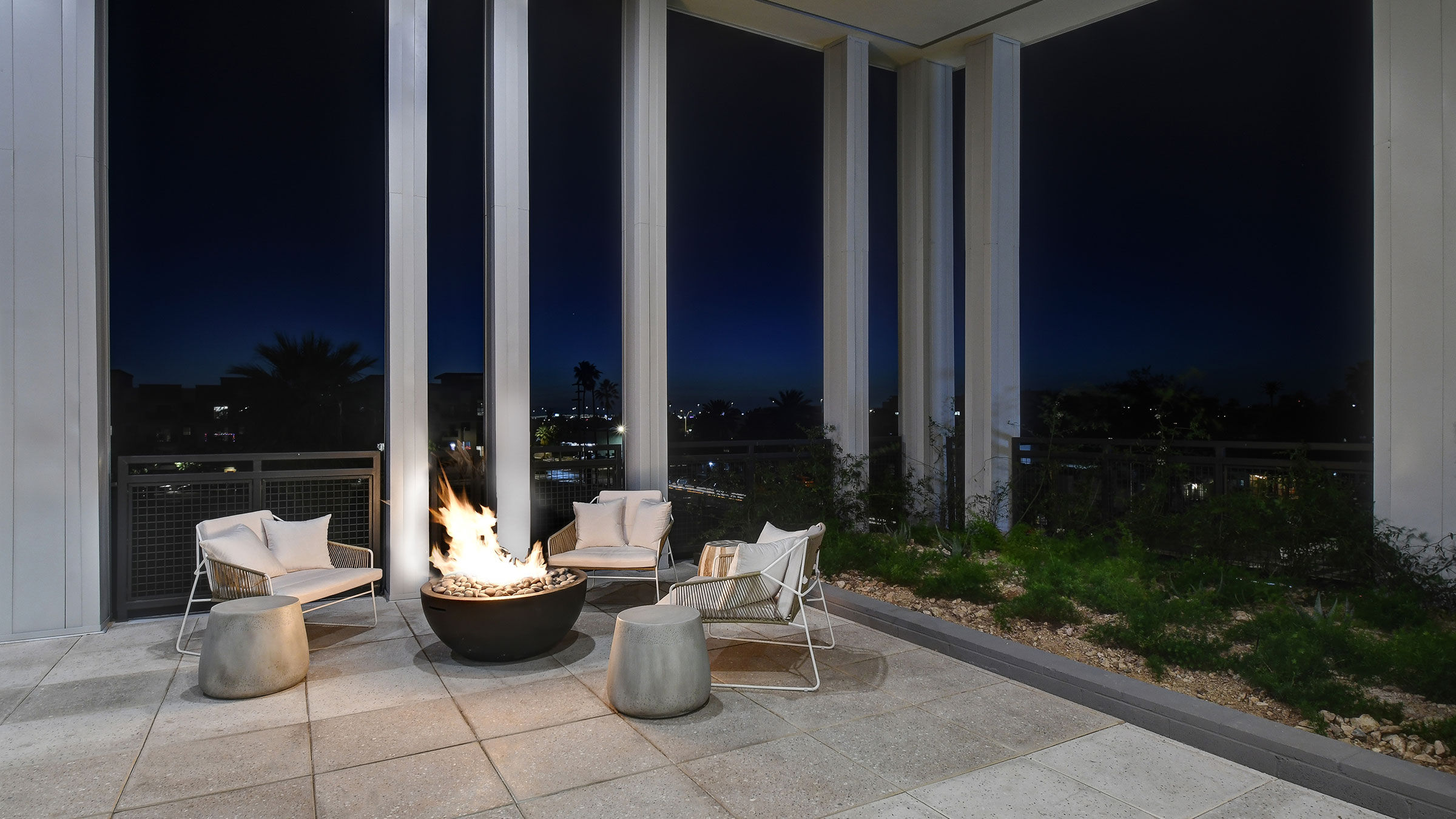 a fire pit with chairs and a fire pit in front of a patio