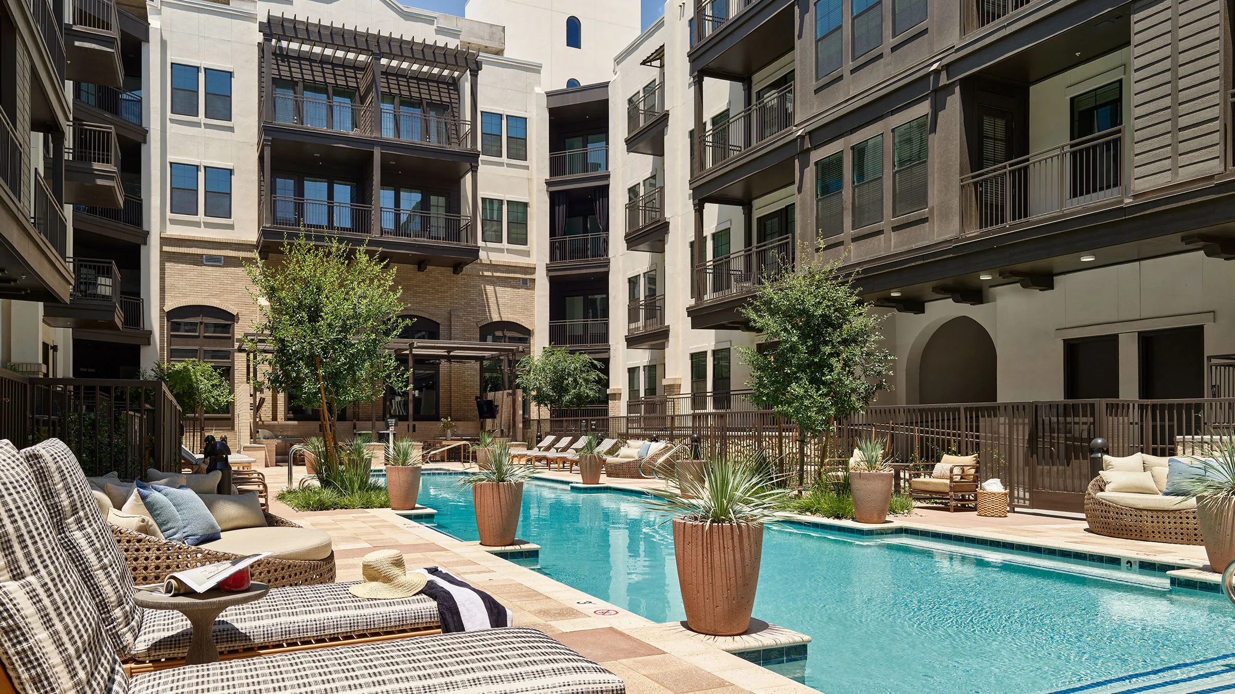 a swimming pool with chairs and trees in front of buildings
