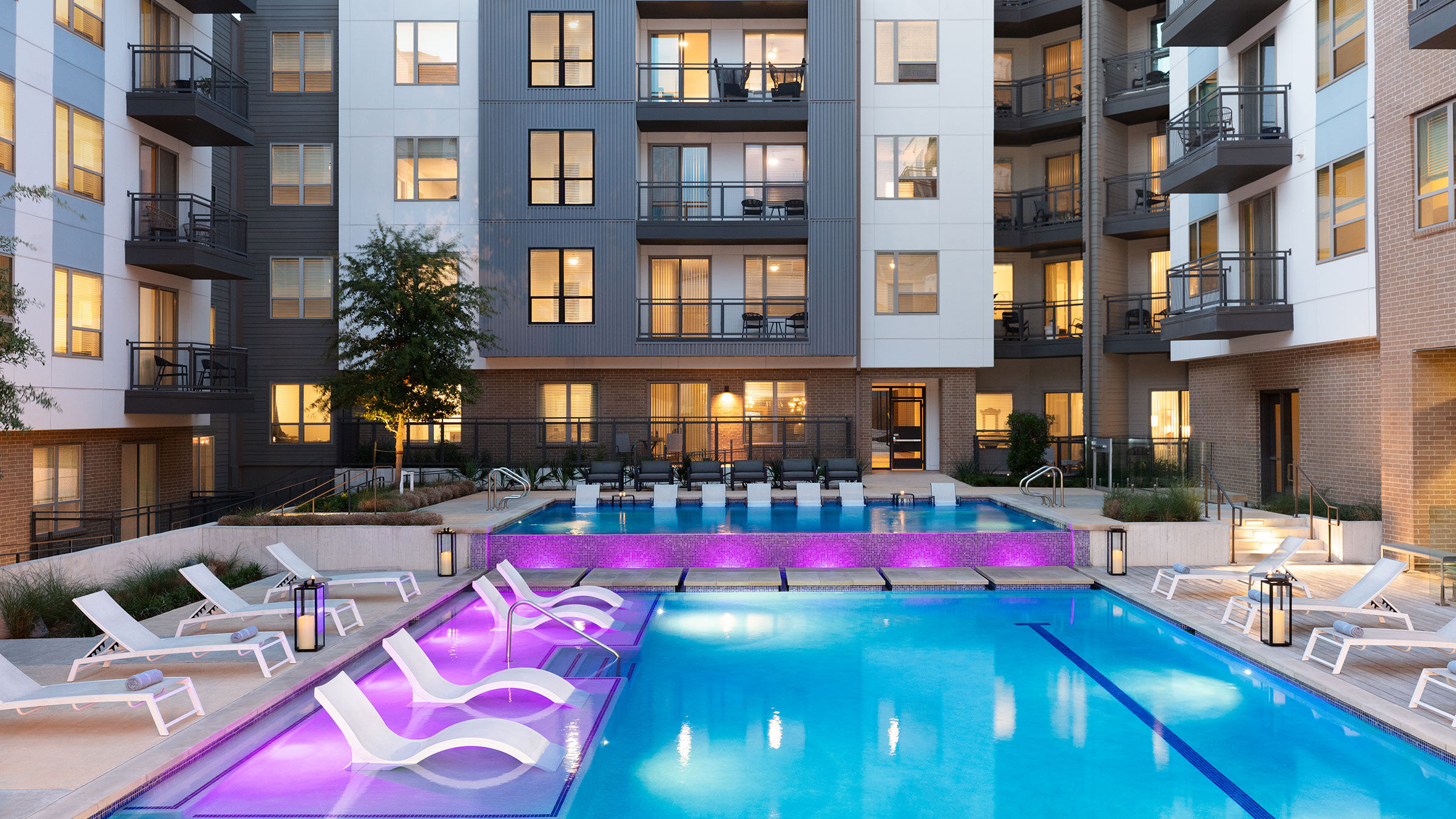 a swimming pool with purple lights in front of an apartment building