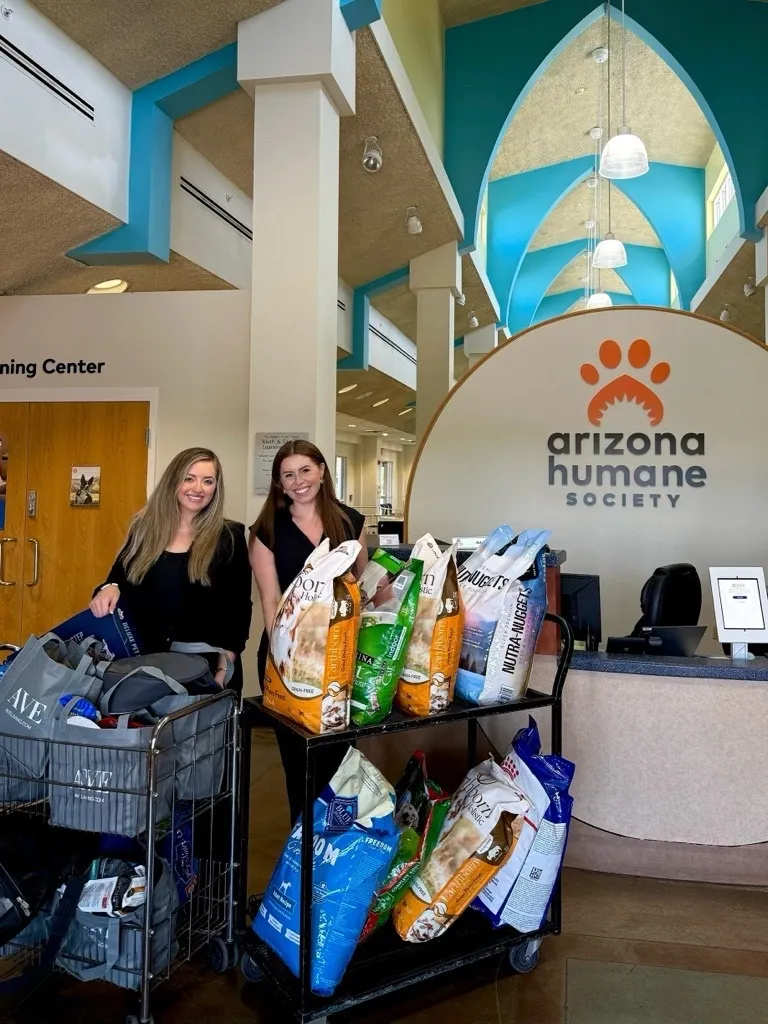 two women standing next to a cart of food