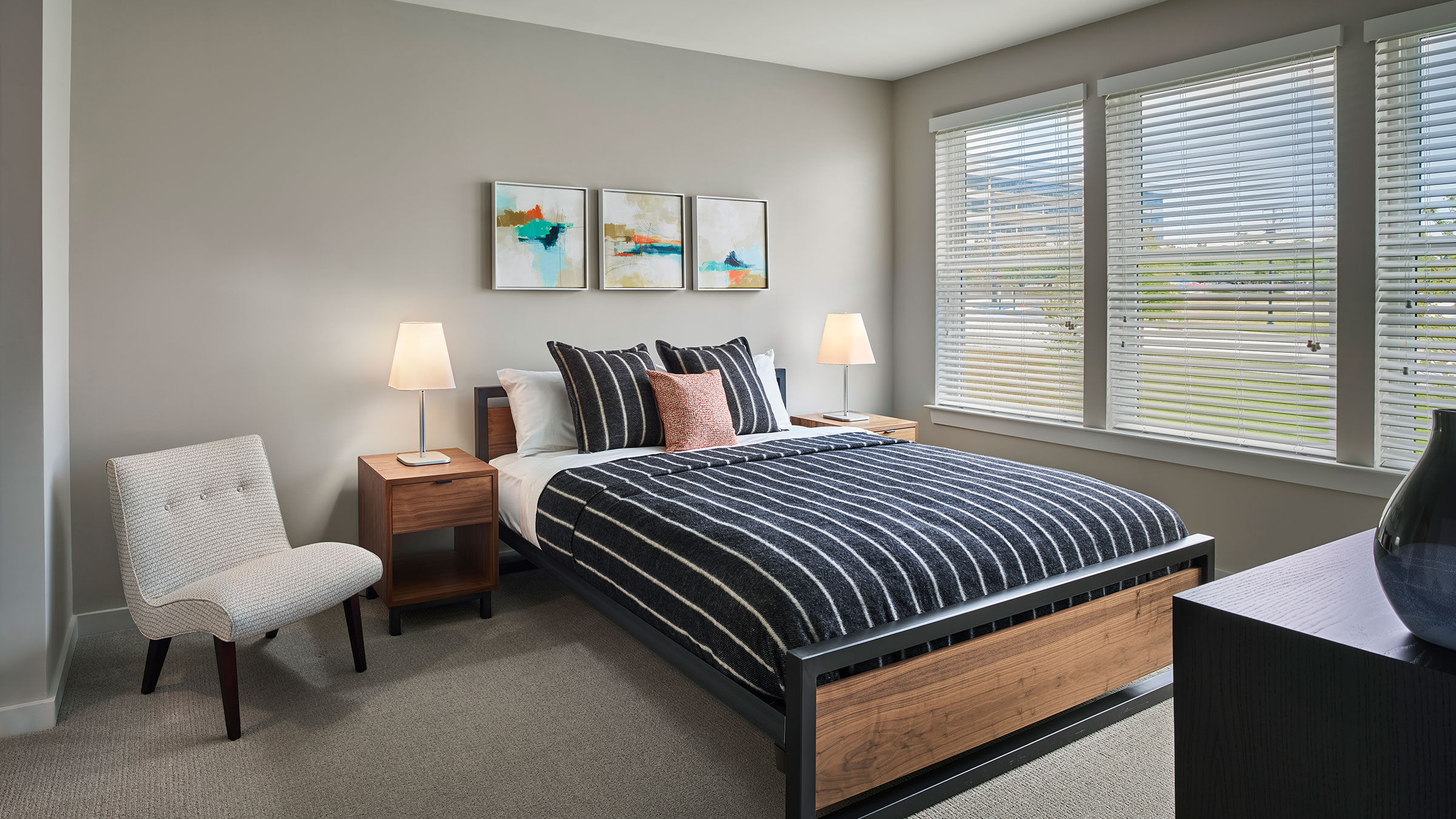 a bed with a striped bedding and a lamp on the side of the bed