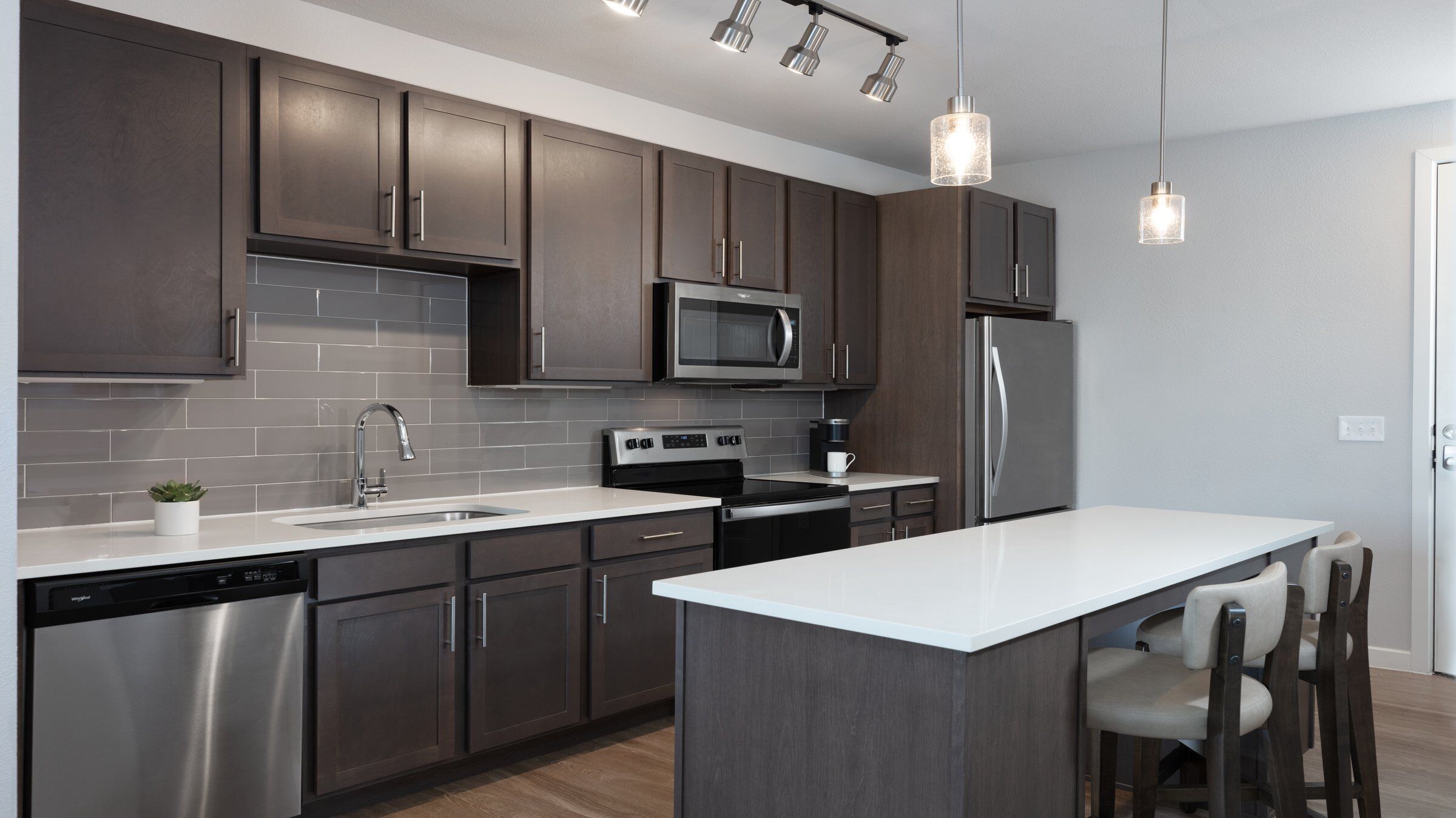 an apartment kitchen with dark cabinets and a white countertop