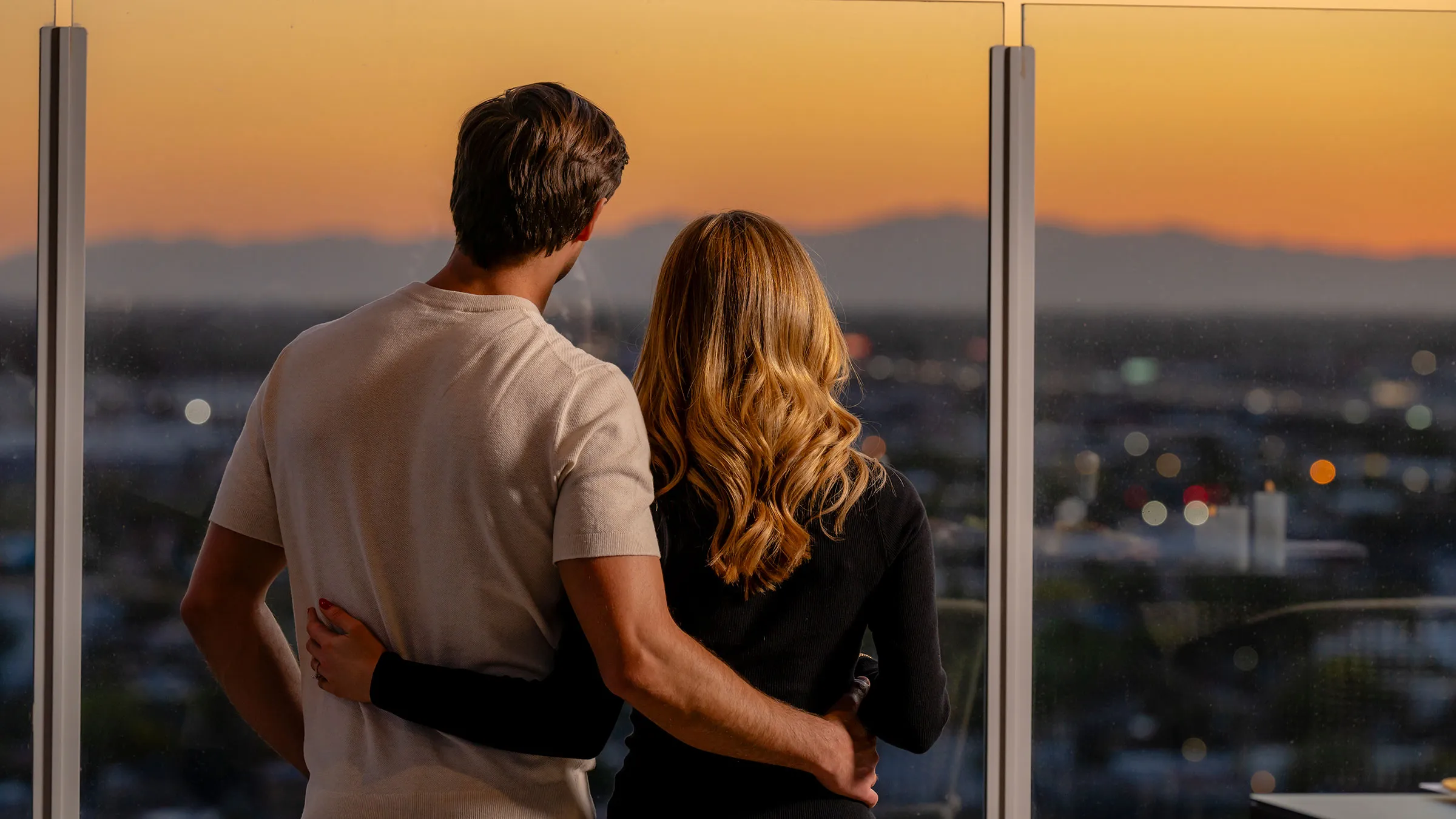a man and woman hugging and looking at a city