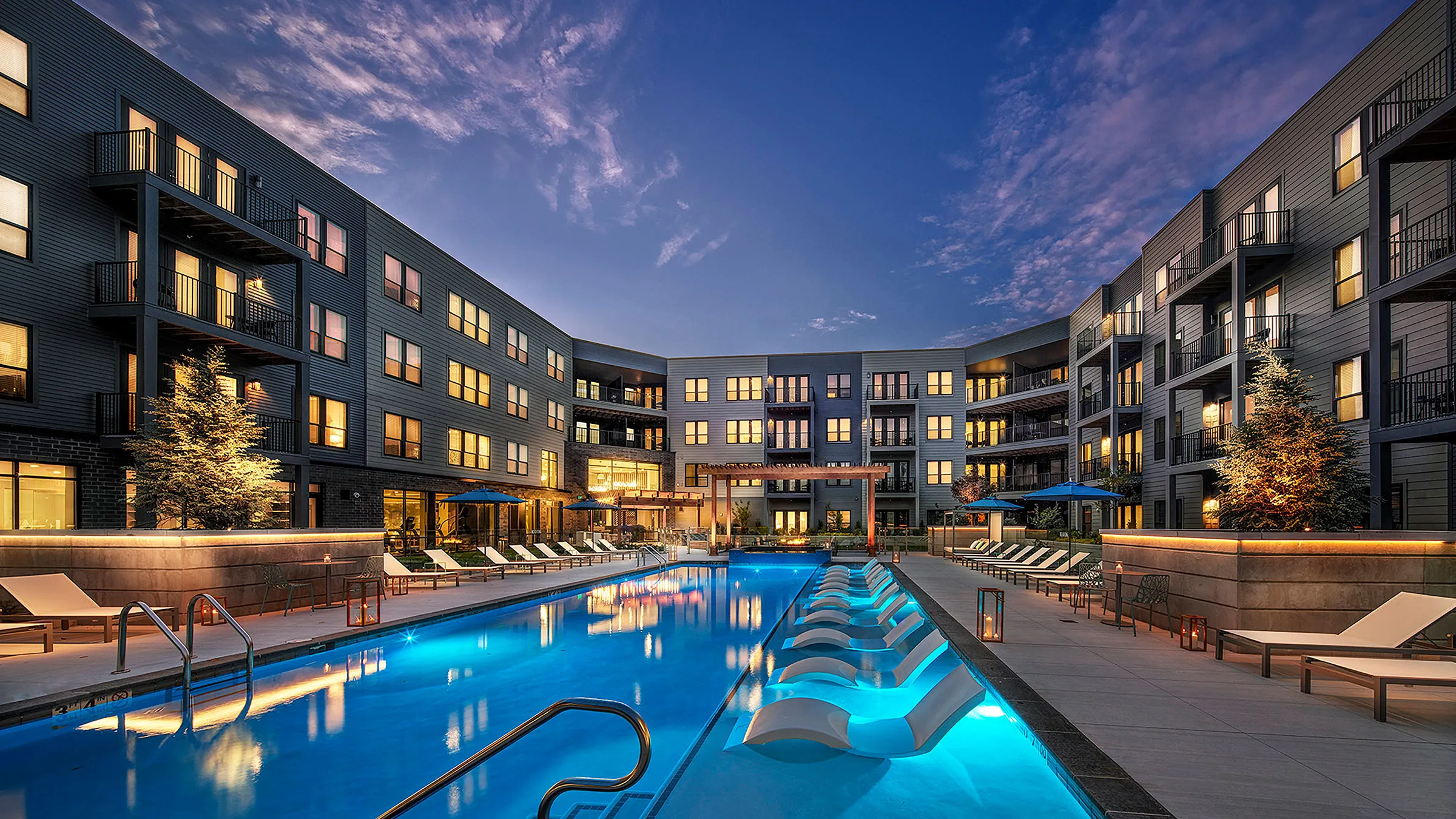 a swimming pool with lounge chairs in front of a building