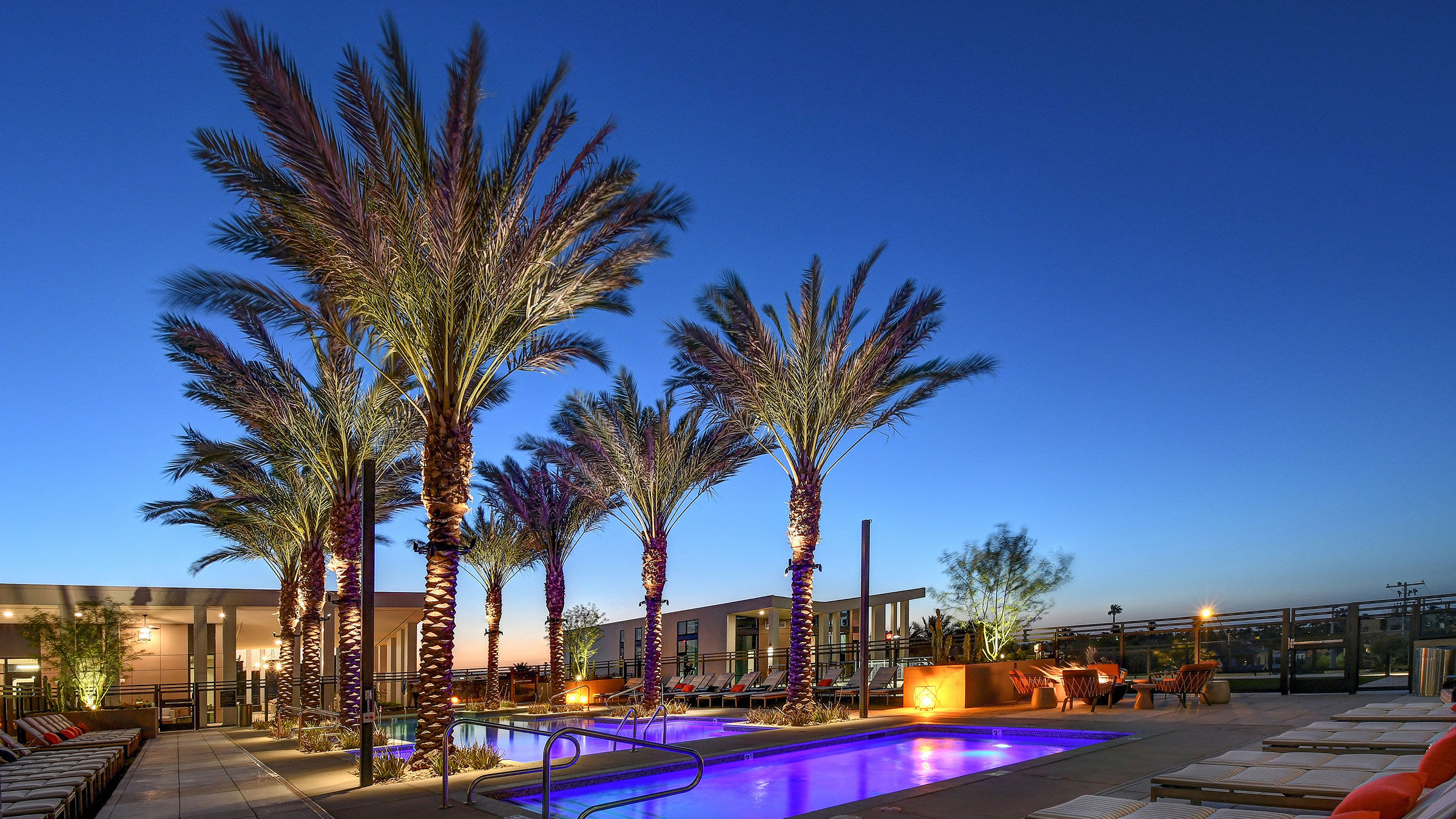 a pool with palm trees and a building with a blue sky