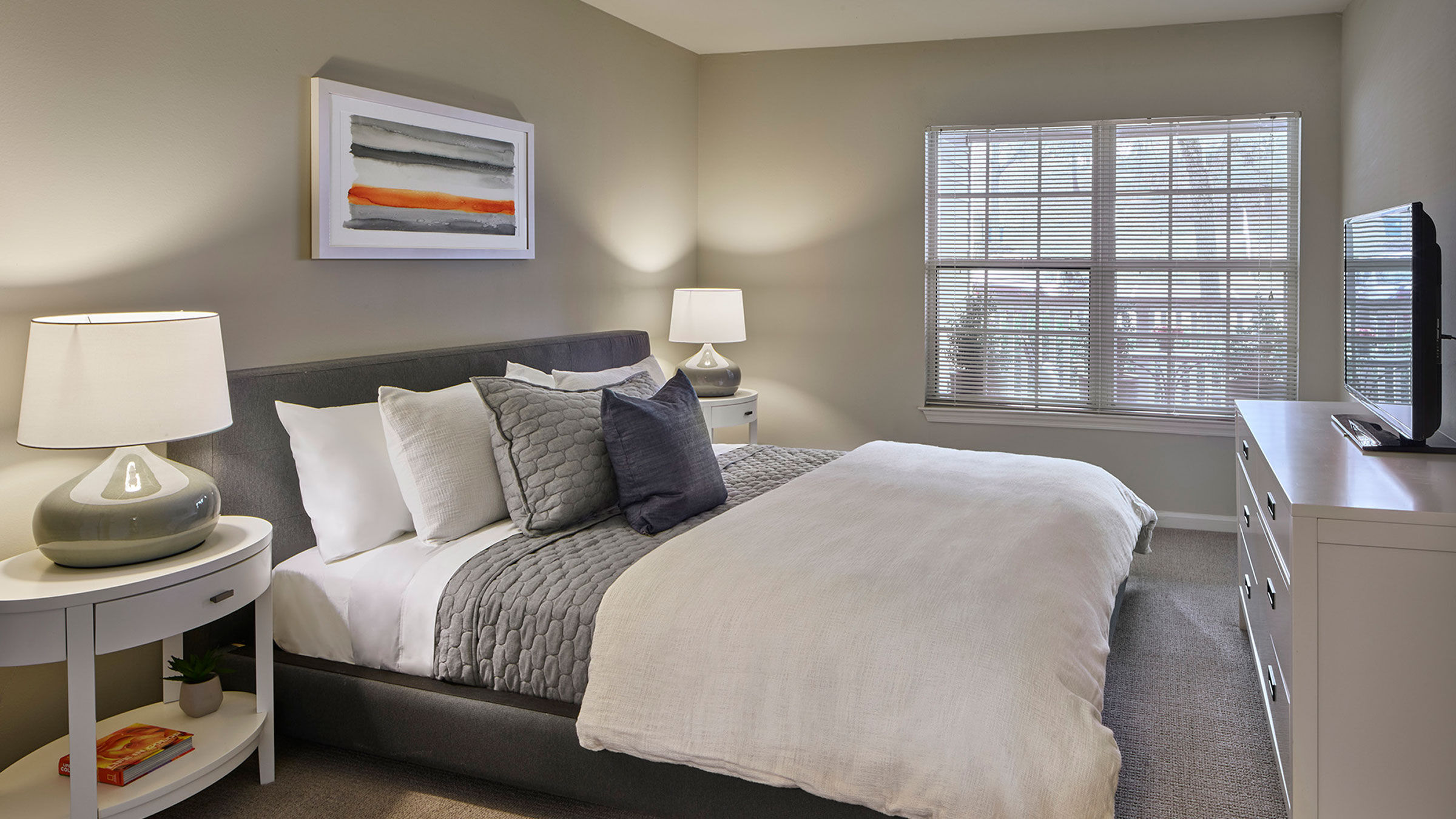 a bed with a lamp and a painting on the wall