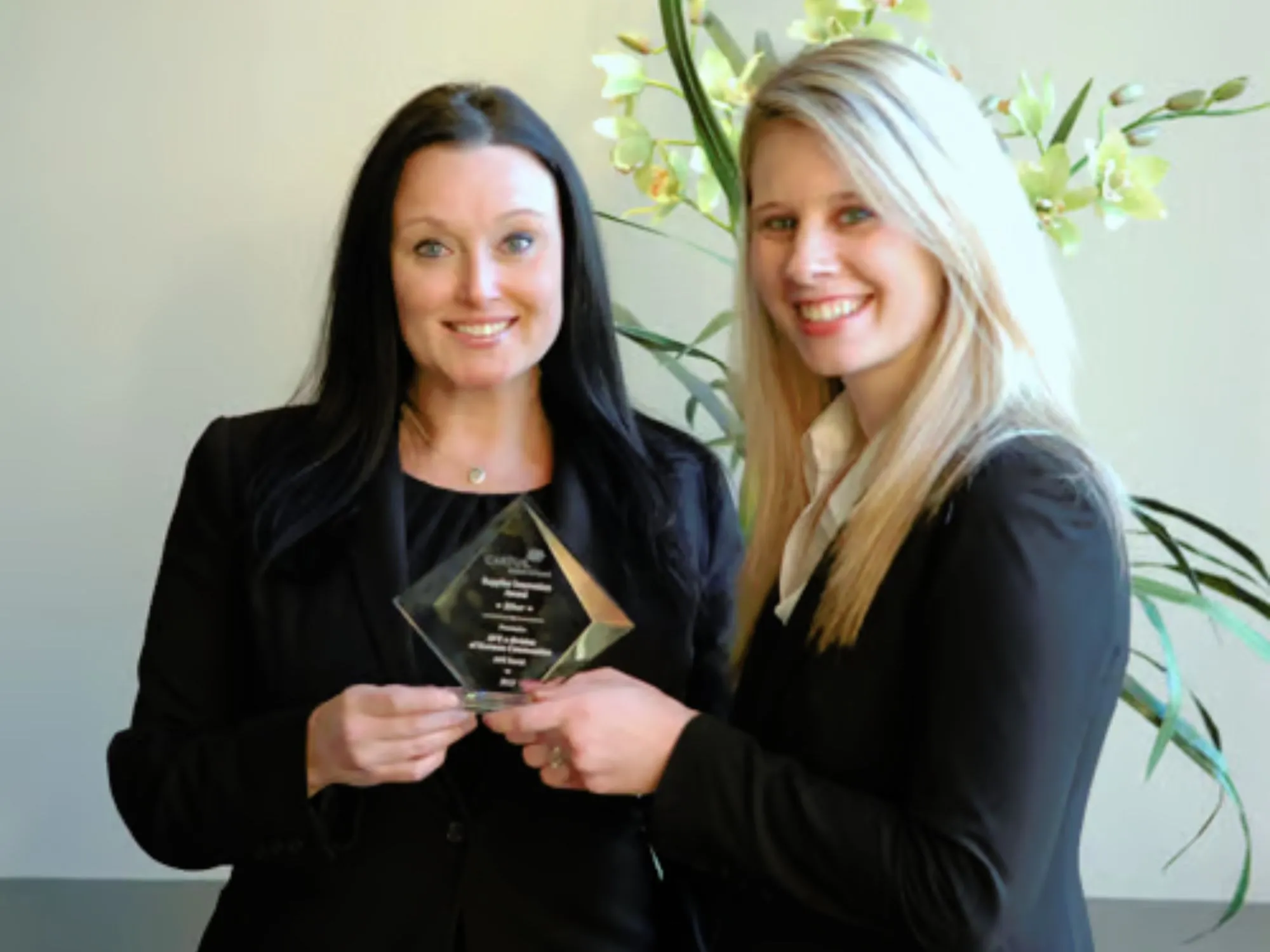 Two women holding up an award 