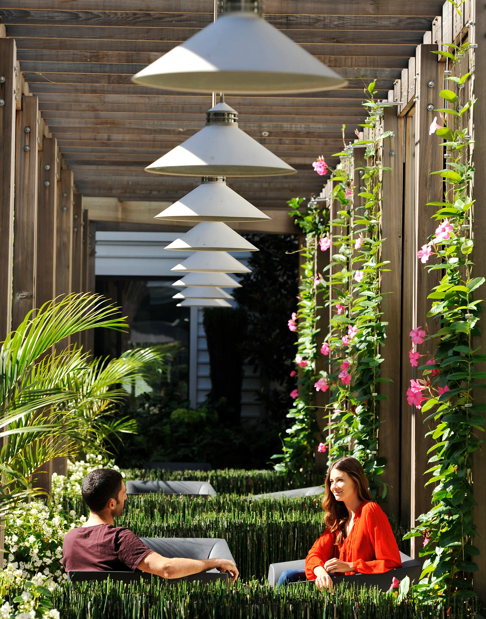 a man and woman sitting on a bench under a shade